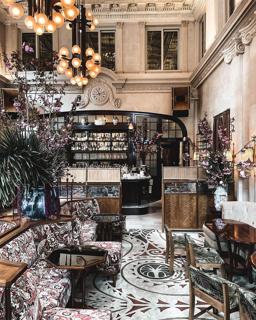 サマンサウィルスのインスタグラム：「2/2 The Lobby Bar in the Nine Orchard Hotel is quite literally, breathtaking. The building was originally built in 1912 as the Jarmulowsky Bank and has been restored to opulent perfection.  The layering and texture, the jewel tone palette, rose velvets and olive tapestries, it's just truly a feast for every sense.  1.	Patterns. Texture. Shape. Perfection. 2.	I took this shot on my iPhone, but to get the true grandiosity of the room and ceiling height I turned the phone on its side and used the 'pano' mode to shoot from floor to ceiling. 3.	The bar, through fresh cherry blossoms. 4.	A little walk through - part 1 5.	A little walk through - part 2 6.	Velvet palm fabric.  7.	The mini banquette seating and smoked mirror tables… 8.	Heavenly Palette: Blush. Rust. Olive. Timber. 9.	A moment for the blush and grey marble bar top. 10.	Matchbooks are the perfect mementos to collect along the way for New York memories.」