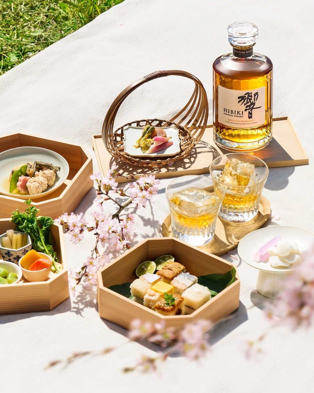 Suntory Whiskyのインスタグラム：「During hanami, participants gather to enjoy a feast of traditional sweets – Gyuhi (soft sweet mochi) and Kohakuto (crystalized jelly candy made with agar agar) – and specially curated lunch boxes known as “hanami bento”. This mix of delicate yet robust flavors presents a perfect complement to the complex yet harmonious taste profile of Suntory Hibiki Japanese Harmony served on the rocks.⁣ ⁣ #SuntoryWhisky #HibikiWhisky #SuntoryTime」