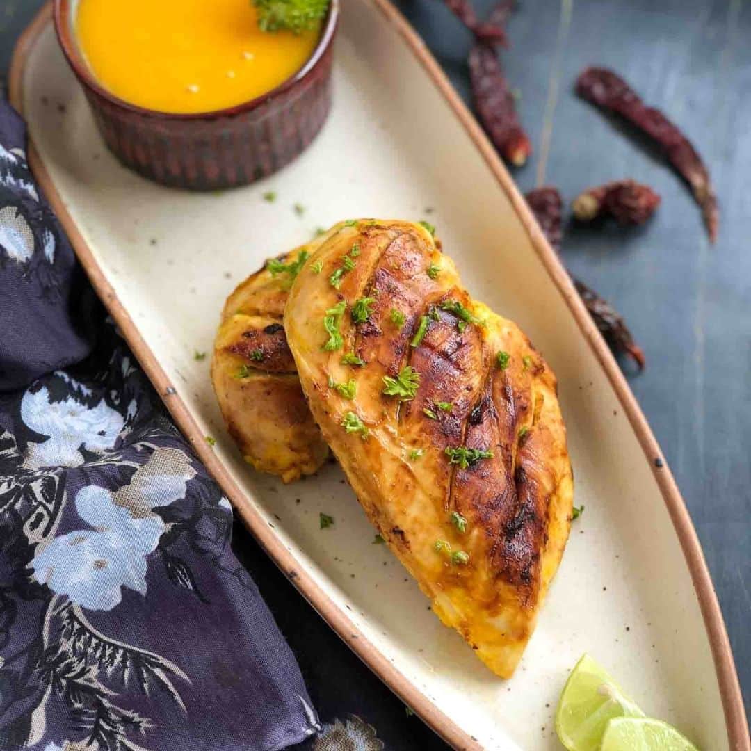 Archana's Kitchenさんのインスタグラム写真 - (Archana's KitchenInstagram)「This spicy Mango Lime Grilled Chicken Recipe is a flavourful dish that can be served either as an appetizer or as a main course dish. A flavour-packed chicken dish with mango and lemon as the star ingredients, this dish will certainly leave your family asking for more.  Ingredients 2 Chicken breasts 1 Mango, made into a puree 2 tablespoons Lemon juice 2 tablespoons Sriracha sauce  1 teaspoon Fish sauce 1 tablespoon Extra Virgin Olive Oil 4 cloves Garlic Salt, to taste Other ingredients 1 teaspoon Honey 1 teaspoon Sriracha sauce 1 tablespoon Corn flour 1/4 cup Water Extra Virgin Olive Oil, to grill the chicken  👉To make the marinade in a mixer jar combine, the ripe mango with sriracha sauce, fish sauce, lemon juice, olive oil and garlic.  👉Grind this into a smooth paste and set aside. You will have approximately 1 cup of the marinade mixture. You can add additional ripe mangoes if you would like more sauce. 👉Wash the chicken breasts thoroughly and make diagonal slits on the surface of the breasts.  👉In a mixing bowl, place the chicken breasts and pour this marinade over it. Marinade for about an hour.  Cover the chicken and keep it aside, while it is marinating. 👉Heat a grill pan on medium heat and brush some oil on it. Ensure the pan is well heated.  👉Once the chicken has been marinated for an hour, place it on the hot grill pan and cook it for about 3-4 minutes on each side, or until well done, ensuring the chicken has cooked through nicely. Ensure not to over cook as the chicken then becomes hard and rubbery. 👉Once it is well cooked, remove it from the pan and allow it to rest on a plate.  👉Transfer the remaining marinade into a saucepan, add in some more sriracha sauce, some honey, and bring it to a single boil.  👉In a small bowl make a slurry of the corn flour along with the water and add it to the saucepan which has the mango mixture brings it to a boil and allow the sauce to thicken. 👉Turn off the heat. Observe the sauce has thickened and has a nice sheen on it.  👉This will be the sauce for our Spicy Grilled Lime & Mango Chicken Recipe. 👉Once done, spoon the Mango Sauce on a platter and place a portion of the grilled chicken and serve hot.」4月25日 14時30分 - archanaskitchen