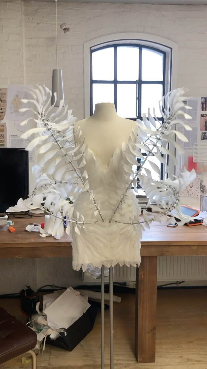 Iris Van Herpeのインスタグラム：「Infinity dress~ in collaboration with artist @Anthony.Howe.Art  The ‘Infinity’ dress is engineered from an extremely fine mechanism that is hand-finished with layers of feathers that fly cyclical around their own centre infinitely. The dress took four months of making. Hundreds of wings were welded by hand with a jewelry welder by Anthony, to then be assembled into four curved axles that are cast into a fiberglass epoxy corset. The ‘skeletal’ clockwork mechanism of the dress is embroidered with fine layers of white feathers, to interact with the wind delicately.  #irisvanherpen #hautecouture」