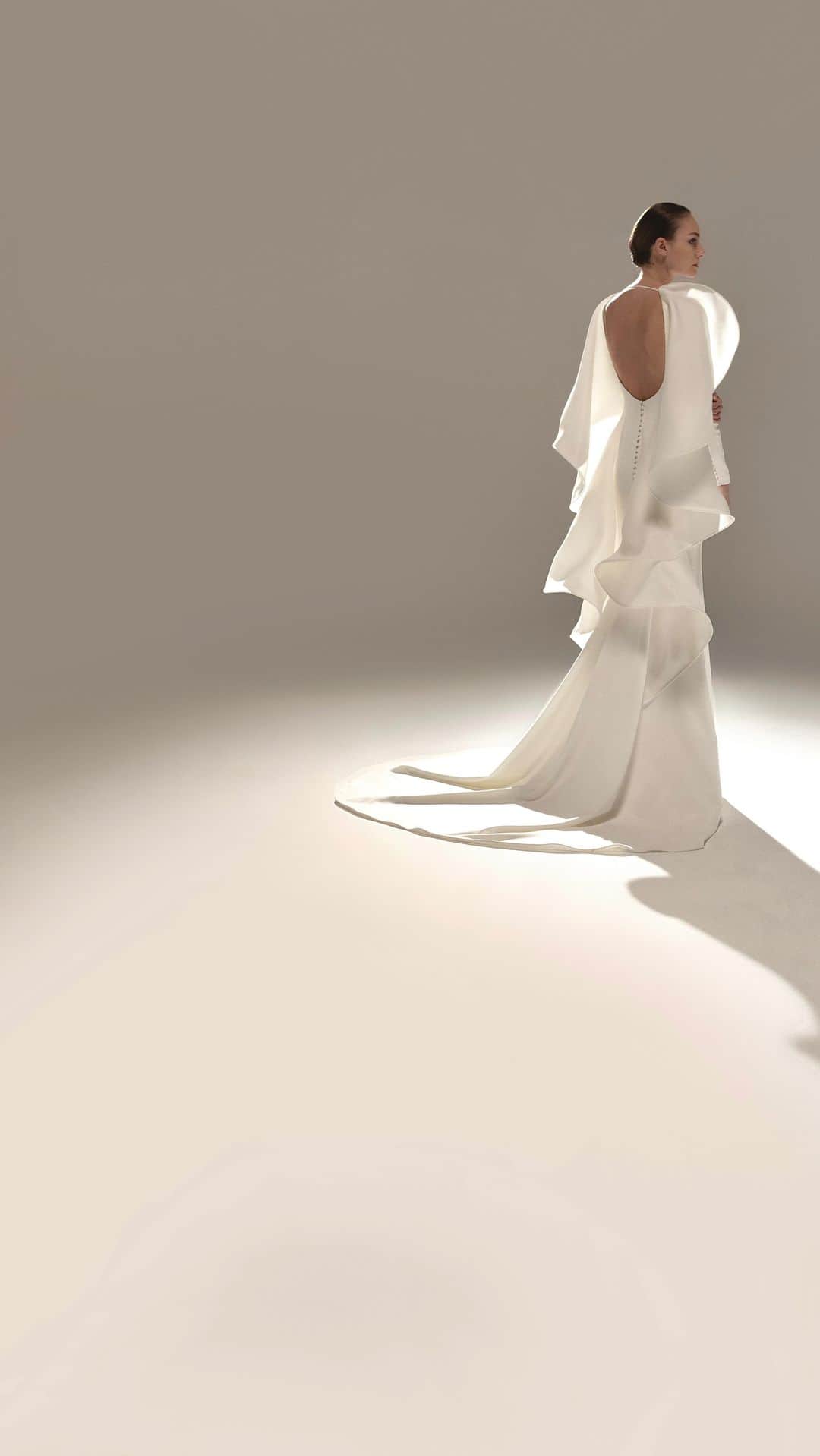 ステファンローランのインスタグラム：「TOUTE UNE VIE  Long sheath dress in white crepe with long sleeves and open back framed by white gazar sculptures, a signature detail of the couturier.   EPURE  A capsule line of 10 bridal gowns available in the Parisian showroom of Stéphane Rolland and partner stores all around the world.  #StephaneRolland #Bridal #WeddingInspiration」