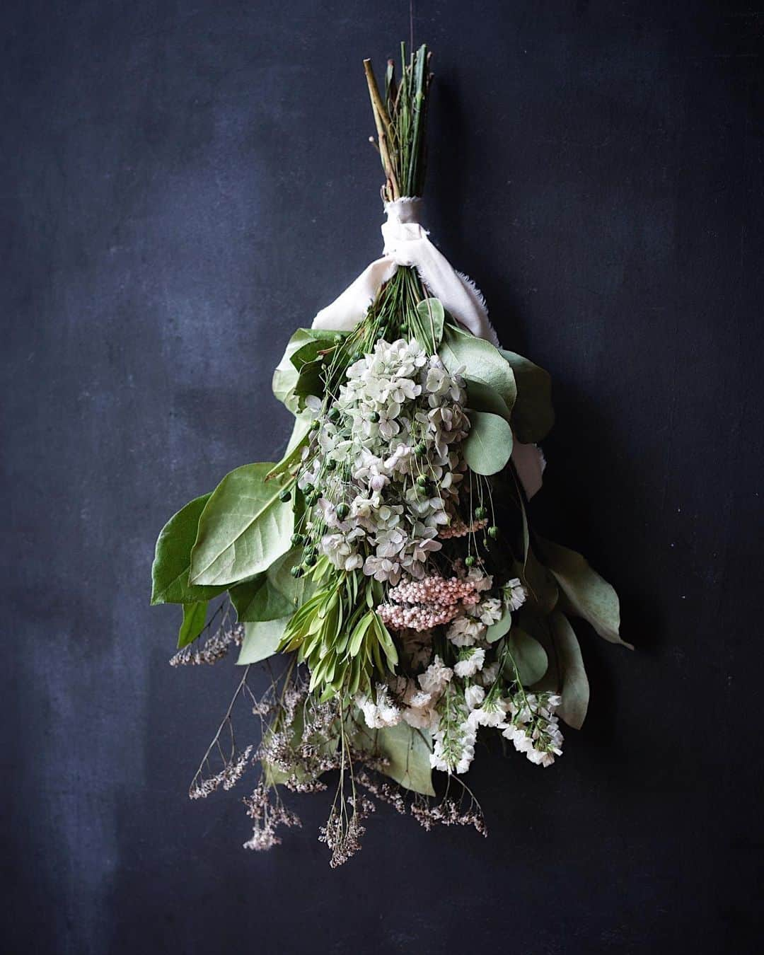 増田由希子さんのインスタグラム写真 - (増田由希子Instagram)「Mother's Day Bouquets (pre-order only) #bouquet #swag #driedflowers #hydrangea   < 母の日ギフト・ スワッグ販売のお知らせ >     「紫陽花と亜麻の実のスワッグ」   手毬のような紫陽花に小花とグリーンを添え、亜麻の実を散りばめました。  亜麻の花言葉は「感謝」。  「いつもありがとう」の想いを込めて、 母の日に、大切な方への贈り物に。  【予約販売期間】 4月27日(木)10時〜5月1日(月) 【お届け日】 5/12(金)、5/13(土)、5/14(日) 但し、遠方（北海道、沖縄）の場合、14日(日)までにお届けできない可能性がございます。 【取扱店】  kanon（山梨） @oyatsu_utatane  プロフィールリンクよりWeb shopにアクセスしてください。 【価格】7,200円 (税別) ※価格には、メッセージカード付きラッピング代が含まれています。 ※別途、送料がかかります。 【サイズ】全長約55cm〜60cm 幅約20cm 高さ約13cm   🌿スワッグには、プリザーブドとドライフラワーを使用しておりますので、長く飾って頂くことができます。  🌿ライスフラワーは、白かピンクどちらかが入ります。(色の指定不可)  🌿ギフト包装について イラストレーター みやしたゆみさんデザインの包装紙とThank youカードを添えてお届けします（今回kanonさんに特別にご用意いただきました）   ※自然素材を使用しております為、花材の一部が変更となる場合がございます。」4月26日 18時09分 - nonihana_