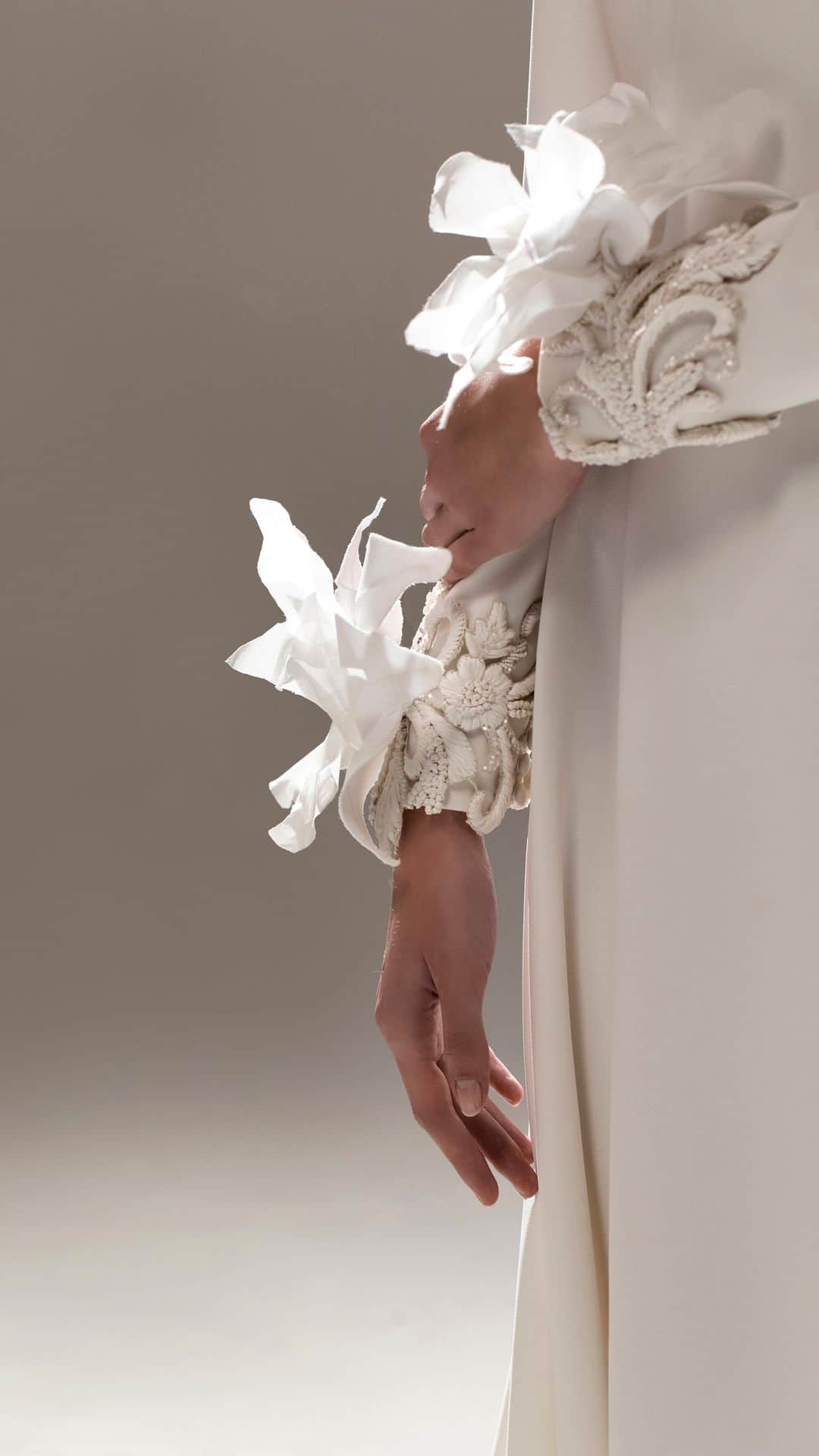 ステファンローランのインスタグラム：「VIVRE POUR VIVRE  Long A line dress in white crepe with long sleeves. Removable cuffs delicately embroidered with petals of gazar and white pearls.   EPURE  A capsule line of 10 bridal gowns available in the Parisian showroom of Stéphane Rolland and partner stores all around the world.  #StephaneRolland #Bridal #WeddingInspiration」