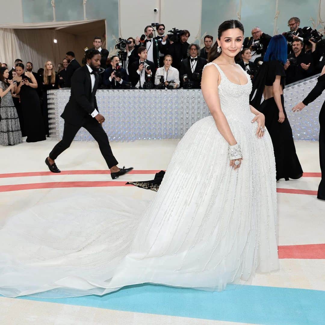 アリア・バットのインスタグラム：「Met Gala — Karl Lagerfeld: A Line of Beauty  I have always been fascinated by the iconic Chanel brides.  Season after season, the genius of Karl Lagerfeld shone through in the most innovative and awe-inspiring couture. My look tonight was inspired from this and in particular by supermodel Claudia Schiffer’s 1992 Chanel bridal look.   I wanted to do something that felt authentic (hello, pearls!) and proudly made in India. The embroidery, made with a 100,000 pearls is a labour of love by @prabalgurung. I’m so proud to wear you for my first Met.   Make up was my go to beautiful glowing sheer skin but this time with wayyyyyyyy more blush to give the look all that romance, rounding it off with a smudgy defined eye with Kajal one the inside (our subtle ode to Karl’s sunglasses 🕶️)   A girl can never have too many pearls… and the right accessories to complement the look which in our case translated to the bow of pearls on my hair.   Oh, and it’s white, for my Choup-ED🐱」