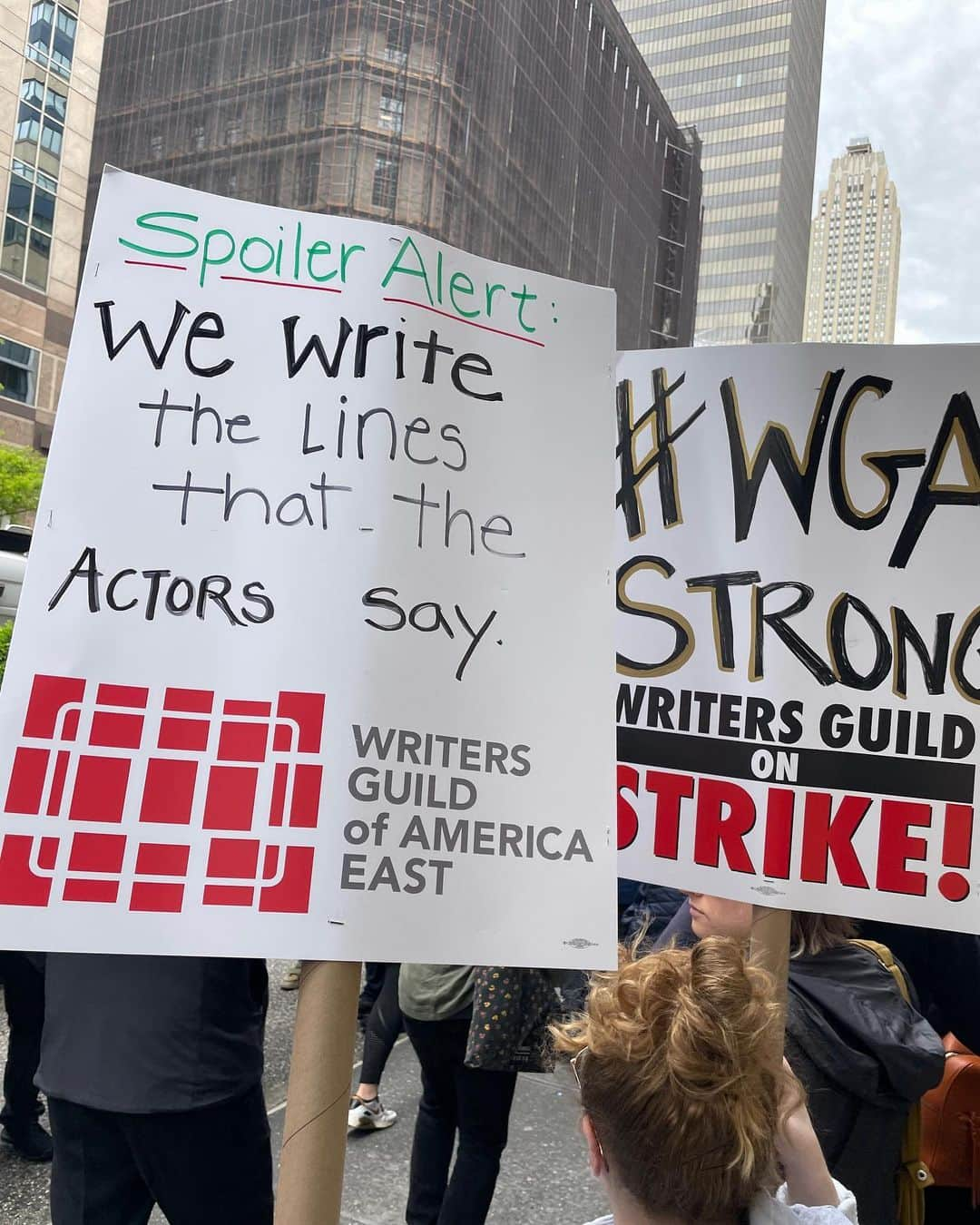 サラ・ラミレスのインスタグラム：「Showing up in solidarity with @wgaeast for the Writers Guild strike and picket line in NYC. Better contracts NOW! The content we consume (and some of us perform 🙋🏽) would be NOTHING without writers. Thank you to all who are showing up to picket, pass out water, coverage, and all who are leading this action. I am here in solidarity as a member of WGA sibling union SAG/AFTRA. Power to the people! Also can I just say how many hilarious and creative picket signs there are? BECAUSE WRITERS WROTE THEM.  . Pic in color of 2 signs in the picket line (I’m holding the one that’s about writing the lines actors say:)) that read: “Spoiler Alert: We write the lines that the actors say. WRITERS GUILD OF AMERICA EAST”, and “#WGA STRONG, WRITERS GUILD ON STRIKE!”」