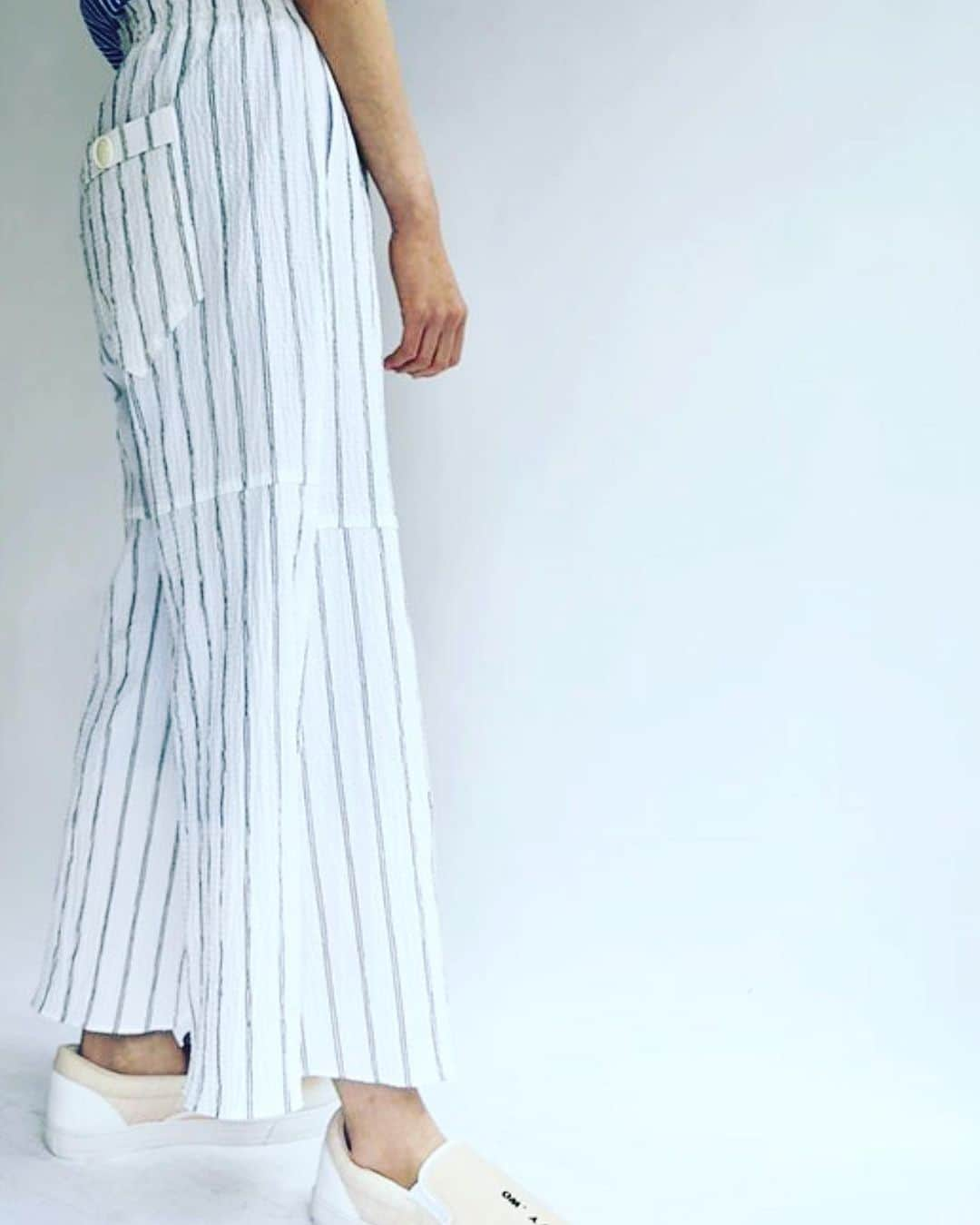 ネイビー ウォのインスタグラム：「cotton stripe flare pants  シルエットの美しさと、清涼感に優れたコットンサッカー・ストライプパンツ。  糸自体が持つ光沢感とプリーツが施されたような独特の表情は、ナチュラルな中にエレガントさもありつつ、形状安定の様な機能性も感じさせてくれ、インポートの様なクセのある価値観を出しています。  生地分量はたっぷりとりつつも、重量を分散させる素材特性や、清涼感ある肌触りとお手入れのし易さはリゾートシーズンにもオススメです。  #navywo #夏服 #素材へのこだわり  @navy.wo_snap_by.staff」