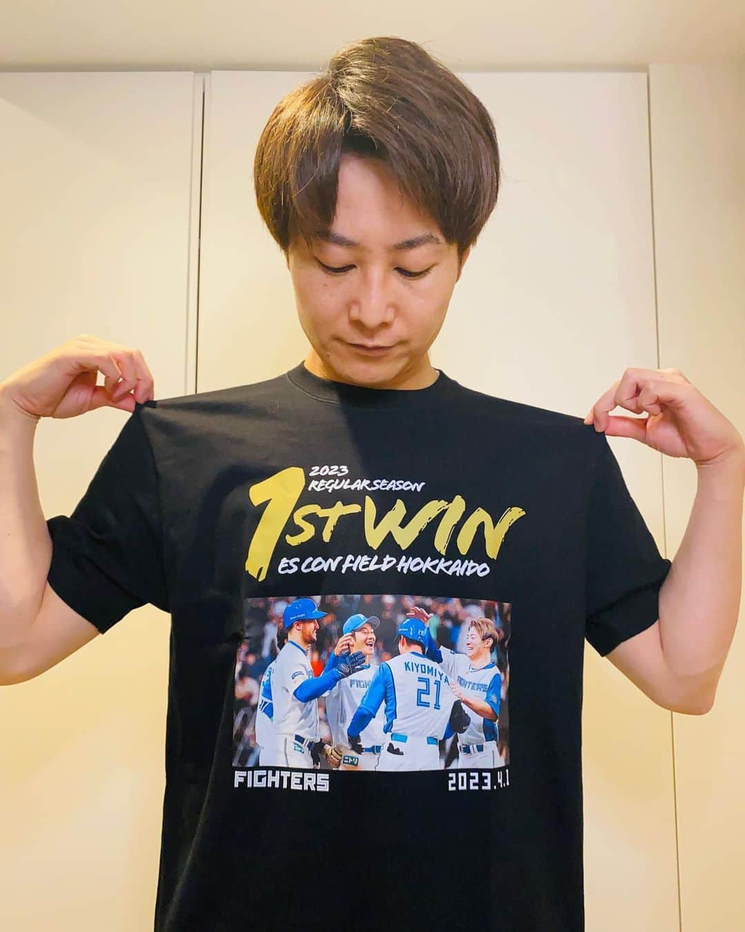 土井悠平のインスタグラム：「エスコンフィールド初勝利Tシャツ㊗️  受注生産のTシャツ注文してたんですが、 届きました🥳  「新時代の幕開けを告げたのは、 清宮のバットでした･･･！！」  エスコンフィールド初勝利は チームにとっても歴史的な1勝ですが、 実況者の土井にとっても特別で歴史的な1勝です🔥  GAORAの実況アナウンサーとして、 初めてファイターズの勝利をお届けできた瞬間でもありました！！しかもサヨナラ😭  個人的な思い出としても この1着を大事にしたいと思います😌  明日からの交流戦、 宜しくお願い致します🔥🔥🔥  ※今回の写真は、彼女に撮ってもらいました😌  #北海道日本ハムファイターズ  #lovefighters  #清宮幸太郎 #エスコンフィールド北海道  #初勝利 #サヨナラ  #新時代 #北海道 #北広島  #セルフタイマー #自撮り  #残念ながら  #セルフタイマー」