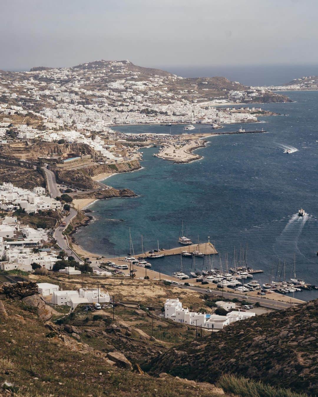 ニューヨーク・タイムズさんのインスタグラム写真 - (ニューヨーク・タイムズInstagram)「A building boom on Mykonos has revealed a “wretched side” of Greece’s recovery.  With more than two million visitors a year, Mykonos is one of the world’s hottest vacation destinations — and a source of prosperity in Greece’s economic revival. Along the island’s famed turquoise coastline, exclusive beach clubs have extended their restaurants onto the fine sand, and luxury retail stores scatter the landscape of the island — all catering to an influx of billionaires, celebrities and influencers.  Since the country’s decade-long financial crisis ended in 2018, Greece has surfed on a recovery fueled by tourism and investment. But recently, a darker side surfaced on the island amid the glamour and tourism, when a state archaeologist who had been documenting building violations on the island was mysteriously attacked, sending shockwaves across Greece. Nowhere has the reaction been fiercer than on Mykonos, where a tightknit coterie of locals have long whispered about illicit and sometimes assertive activity by deep-pocketed developers, and a lax enforcement system that they say enables anyone with enough money to operate above the law. The Greek government has carried out a swift crackdown.  Apart from its Instagram glam, Mykonos happens to be one of Greece’s most important locations for antiquities. To preserve the country’s treasures, the Culture Ministry’s archaeologists inspect land before new structures are built. Twelve ancient sites were discovered within eight years on Mykonos during excavations for building foundations, halting construction in some cases and forcing relocation in others. Houses have sprung up like mushrooms along mountain slopes and in areas that had been classified as “unbuildable,” and some villas are larger than authorized.   Tap the link in our bio and read more about the building boom happening on Mykonos and what the future looks like for the island. Photos by @marcoandres」5月30日 2時52分 - nytimes