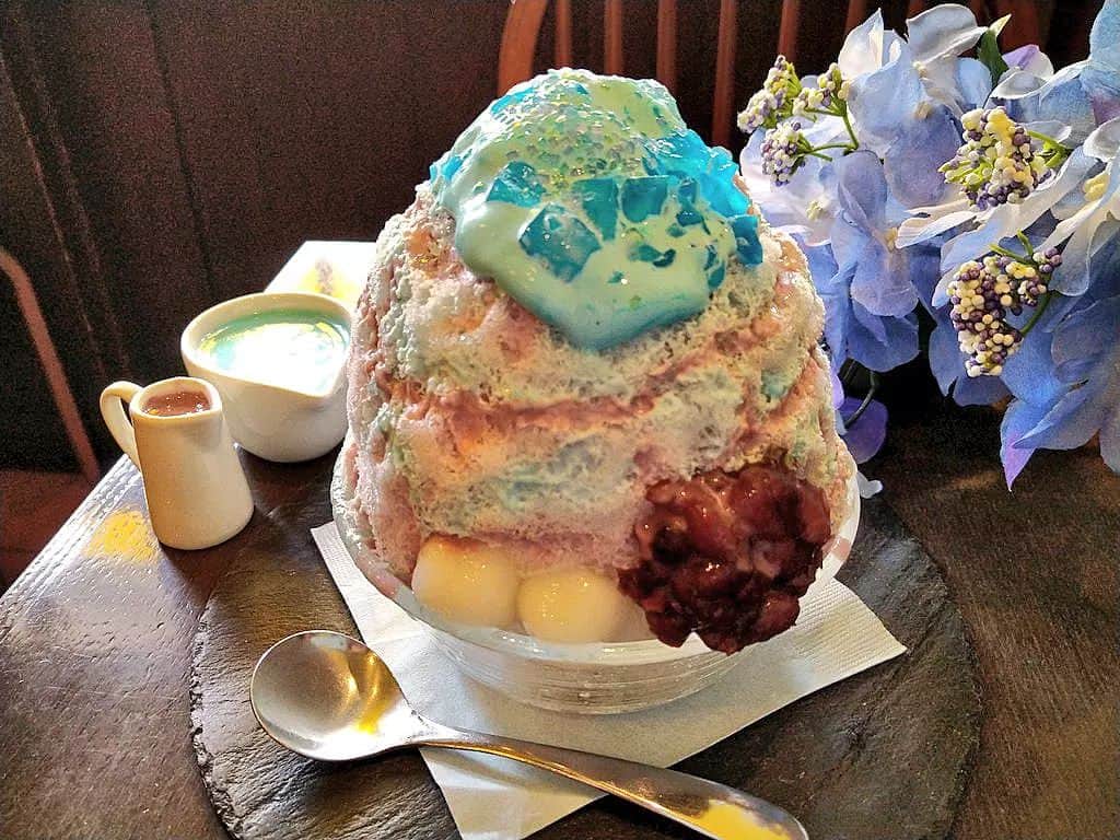 おいもカフェ金糸雀のインスタグラム：「. 梅雨の鎌倉の紫陽花をイメージした新作「あじさいかき氷」(税込950円)。 純氷で作るふわふわの氷にかかった、まろやかな紫芋ソースと爽やかなミントソースで、あじさい寺に咲く紫と水色の紫陽花を表現しました。 さらにソース上にミントホイップとミントゼリー、ジュエリーシュガーを重ねがけし、雨に濡れる紫陽花の艶感を演出。 氷の下にはチョコミントアイスを忍ばせ、最後までミントの味を楽しめるようになっております♪ 5月下旬頃から8月下旬頃までの夏季限定。  #おいもカフェ金糸雀 #おいもカフェ #鎌倉 #小町通り #湘南 #神奈川 #カフェ #鎌倉カフェ #湘南カフェ #神奈川カフェ #鎌倉スイーツ #鎌倉グルメ #鎌倉観光 #鎌倉旅行 #鎌倉散歩 #鎌倉デート #あじさいかき氷 #かき氷 #紫陽花 #あじさい #明月院 #長谷寺 #ミント #チョコミント #紫芋 #チョコミン党 #chocolatemint #초코민트 #kamakura #가마쿠라 . 《おいもカフェ金糸雀》 営業時間：10:00-18:00(L.O.17:30) 定休日：水曜日 248-0006 神奈川県鎌倉市小町2-10-10 小町TIビル1F TEL：0467-22-4908」