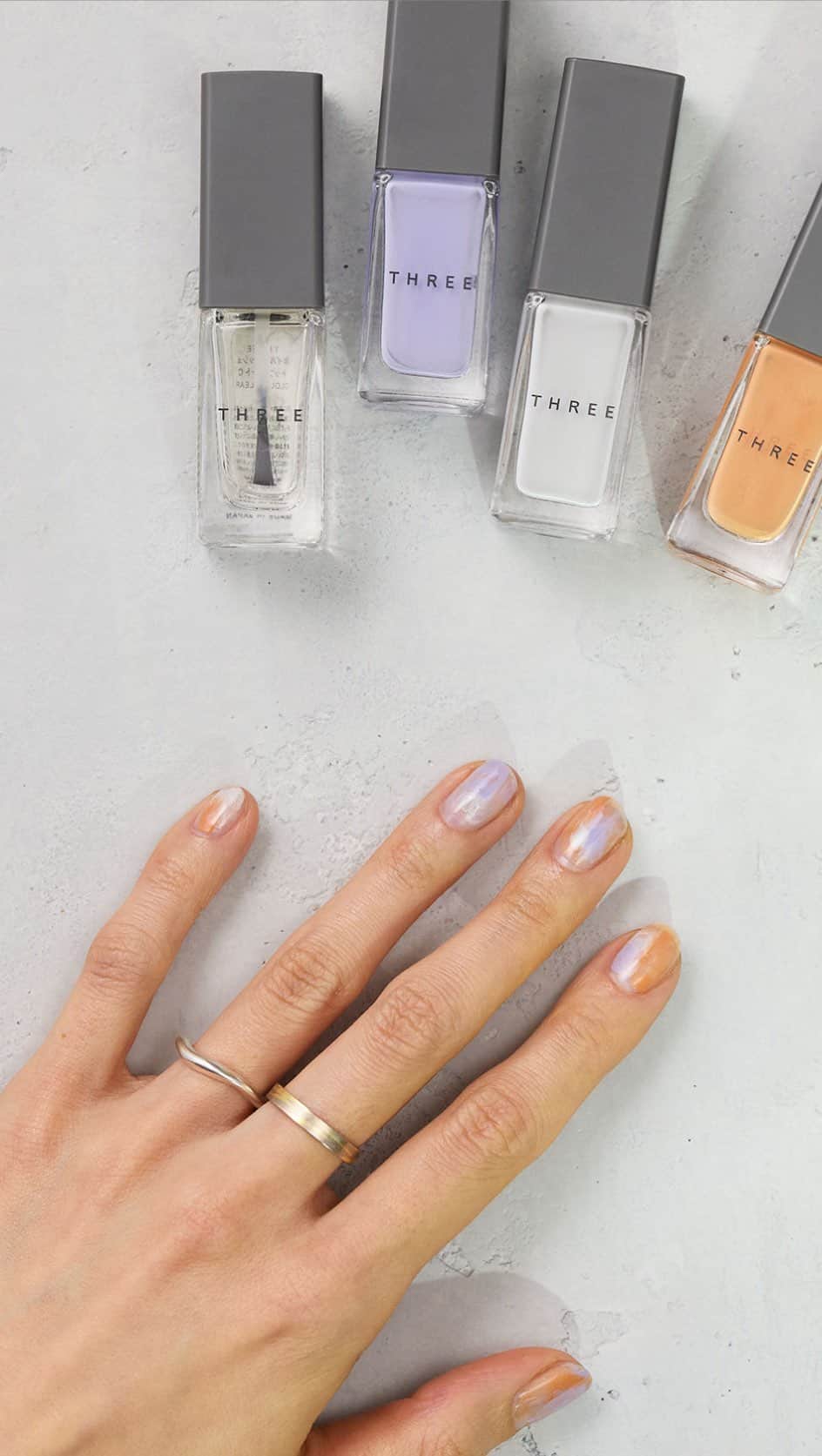 THREEのインスタグラム：「〈SUMMER NAIL IDEAS Vol.1〉 THREEクリエイターに聞いた、夏のファッションにぴったりなオススメのネイルアレンジ。 水面のようなニュアンスが、透明感のある手もとに。  〈HOW TO〉 1. ランダムにネイルポリッシュを点でおく。 2. 点でおいたネイルポリッシュを、トップコートでぼかしていく。 3. カラーが乾いたら、最後にトップコートをもうひと塗り重ねて仕上げる。  〈使用アイテム〉 ・THREE ネイルポリッシュ 132 BREATH OF WIND ・THREE ネイルポリッシュ 133 COLOR OF DREAMS ・THREE ネイルポリッシュ 136 HEROINE HONEY ・THREE ネイルポリッシュ トップコート  #threecosmetics #ネイルアレンジ #夏ネイル」