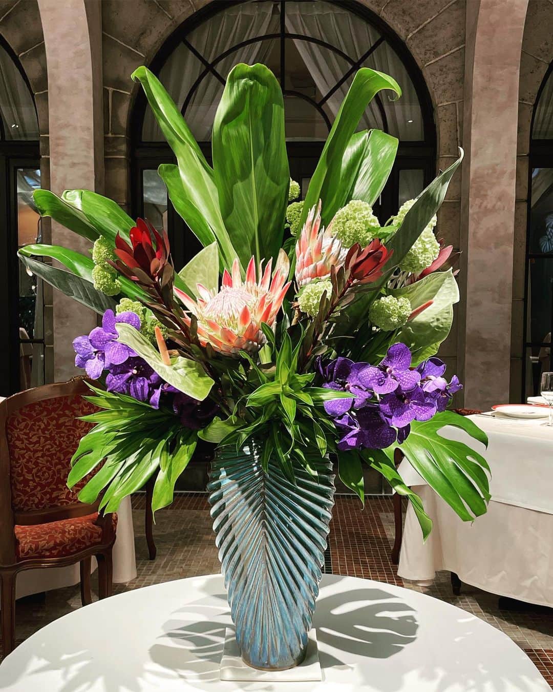 Leau a la boucheのインスタグラム：「皆様、ゴールデンウィークいかがお過ごしでしたか。✈️  今週のダイニングのお花は夏っぽくキングプロティアを中心に生けて頂きました。中目黒フラワーズネストさんの作品です！エルテの作品だけでなくお花も楽しめますよ💐🌼  ドラセナ ・キングプロティア ・ビバーナム ・リューカデンドロ・アンスリューム ・バンダ #フランス料理 #渋谷 #おはな  #メゾンドミュゼ東京青山  #洋花 #1999  #洋館 #グランメゾン #表参道 #フラワーズネスト中目黒」