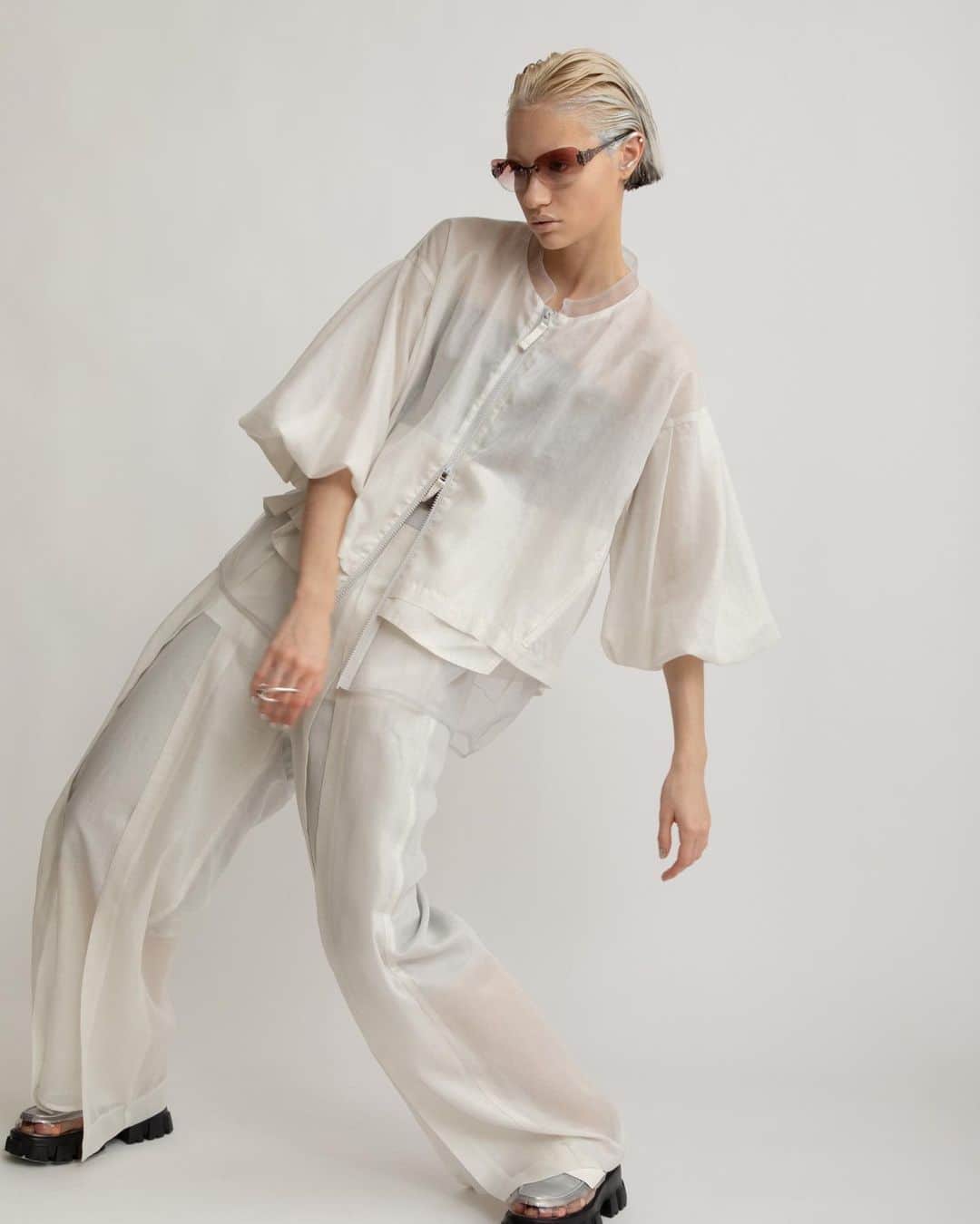 AULA AILAのインスタグラム：「【2023 HIGH SUMMER COLLECTION】  HALF SLEEVE LAYERED BLOUSON COLOR WHITE SIZE 0 ¥25,300  薄手のレザーのような光沢感と本来のスパンボイルの透け感が相まって、新鮮な印象に。  タックでボリュームたっぷりな5分袖のブルゾンです。  春から晩夏にかけて、長く着られる、軽い羽織りです。  見頃は内側にチュールがレイヤードされているため、裾からチュールが覗き、シアー感が涼し気なデザイン。  オーバーシルエットで、後ろはフレアーで裾が長いので、ヒップまわりをカバーしてくれて安心。   SLIT LAYERED PANTS COLOR WHITE SIZE 0/1 ¥24,200  薄手のレザーのような光沢感と本来のスパンボイルの透け感が相まって、新鮮な印象に。 フロントは大胆なスリットになっていて、内側にパンツがレイヤードされています。 動くとスリットが開くデザインが、軽やかでアクティブ。 穿き心地はリラックス感がありながら、光沢感とデザインによりきれいめな印象なのでTシャツなどラフなアイテムを合わせてもカジュアルになりすぎないアイテムです。 ウエストベルトの後ろのみゴム入りなので、締め付けられないノンストレスです。   ✔️AULA AILA OFFICIAL WEB STOREにて HIGH SUMMER COLLECTIONアイテム展開中！」