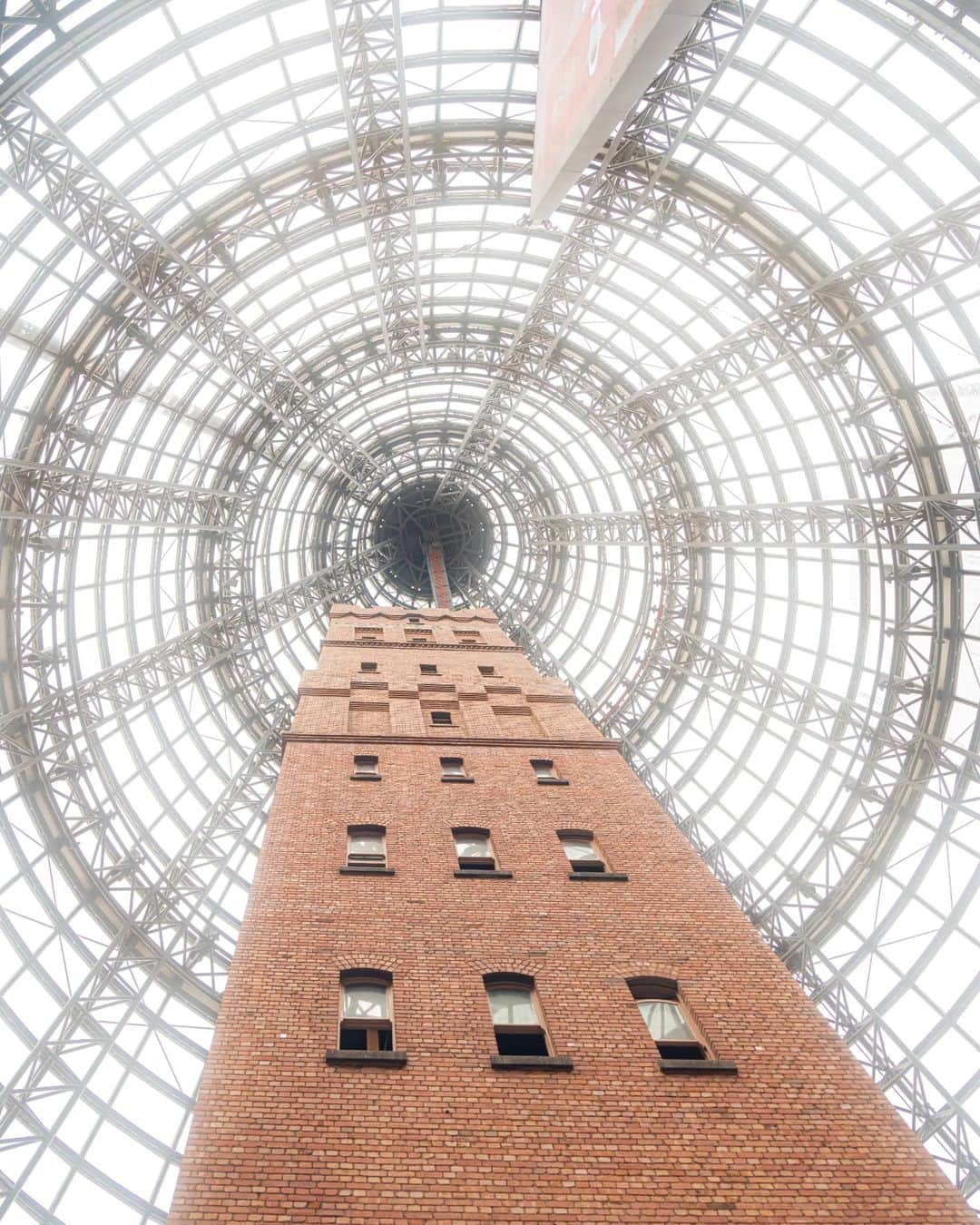6151のインスタグラム：「MELBOURNE CENTRAL｜オーストラリア メルボルンの旅  1889年に建てられた歴史的建造物「クープス散弾製造塔（The Coop's Shot Tower）」を覆うように建てられた円錐型の「The Glass Cone」。  日本人の建築家 黒川紀章氏が設計したメルボルンの歴史的建造物でもあるショッピングセンター「メルボルン・セントラル」内に聳え立つ姿は圧巻だった。  クープス散弾製造塔は高さ50m、その上に900枚を超えるガラスのアトリウムというなんだか嘘みたいな景色で見上げていると何が現実かわからなくて混乱してくる。  ショッピングセンターなのでお買い物も楽しめる！メルボルンおすすめのお土産屋さん紅茶専門店「T2」も入った館なのでふらっと覗いたり。お買い物たくさんしたくなるなー。  @newt_guide #NEWTでメルボルン #NEWTモニターツアー #visitmelbourne」