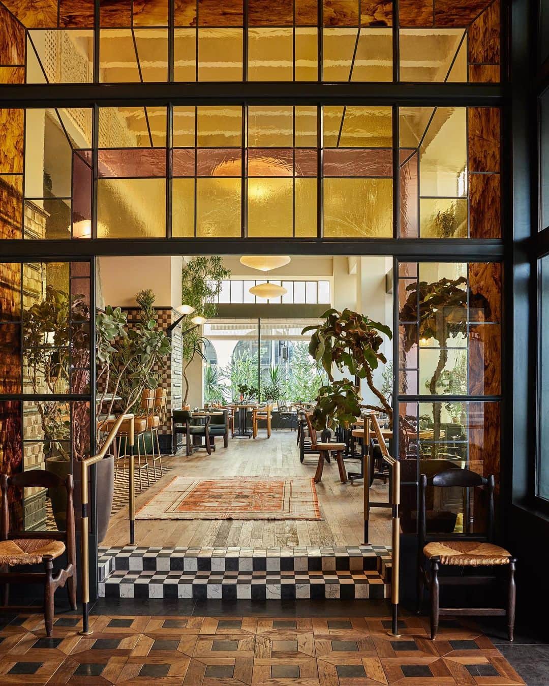 ケリーウェアスラーのインスタグラム：「OPEN INVITATION. At the @downtownlaproper a stained-glass portal leads guests to the restaurant Caldo Verde. The furniture used in the space is a mixture of bespoke pieces and vintage finds, with plants sourced from Inner Gardens. Sconces were commissioned and created to work together with the hanging Akari Light Sculptures by Isamu Noguchi. XK」