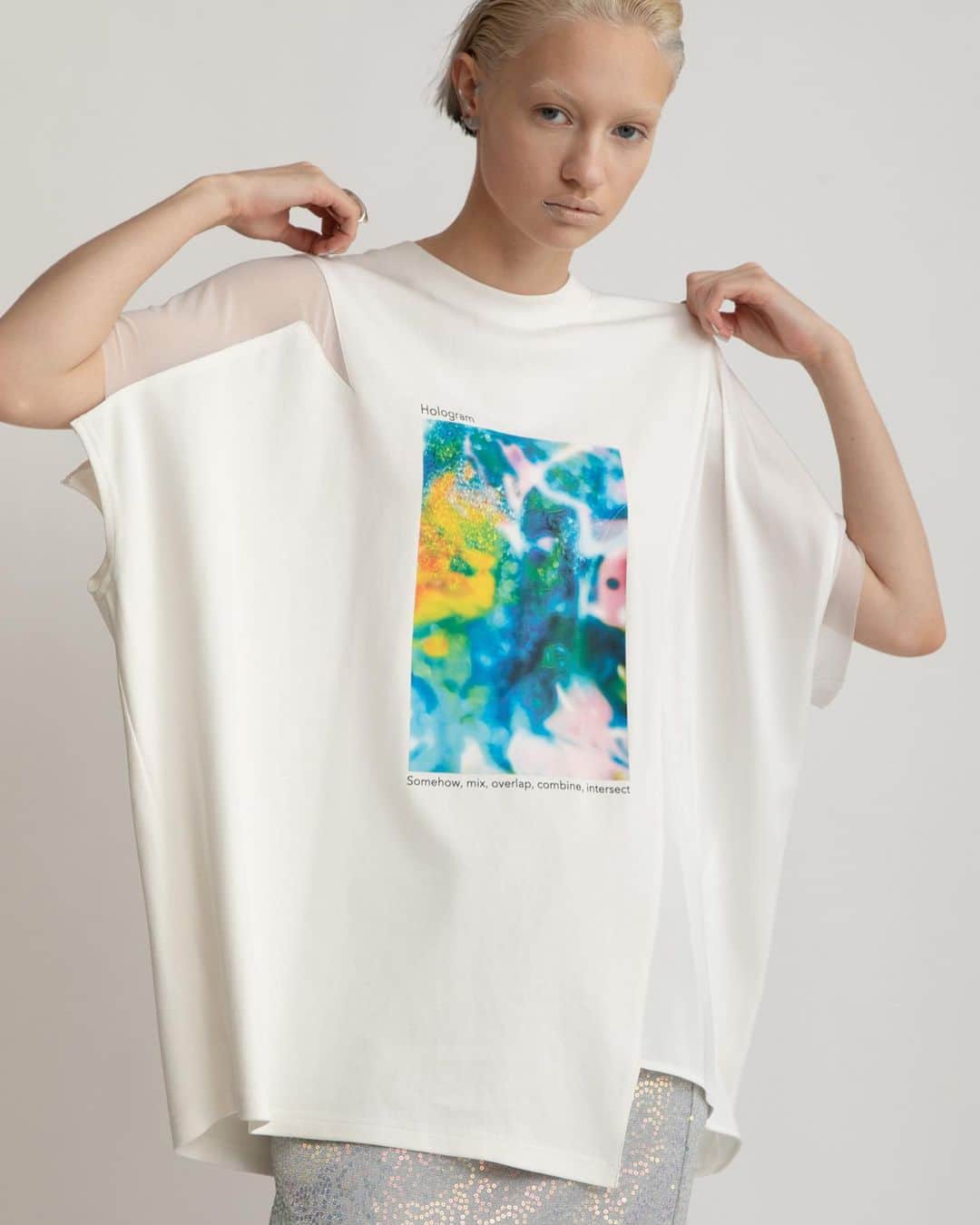 AULA AILAのインスタグラム：「【2023 HIGH SUMMER COLLECTION】  HOLOGRAM PHOTO T-SHIRT COLOR WHITE×BLUE SIZE 0 ¥16,500  今季のシーズンテーマ“Hologram”をイメージしたフォトプリントTシャツ。 メタリックやオーロラの素材に光を当てて撮影した写真にカラーを混ぜ、重ねたりしてグラフィック加工しました。  見頃はコットンスムース生地を斜めに切り替え、左脇見頃にはサテン、右肩、左袖口にはチュールをアシンメトリーに、リメイク風にコンビネーションしたデザイン。 横に幅広いオーバーサイズのたっぷりしたシルエットとグラフィックが目を惹くTシャツ。  ✔️AULA AILA OFFICIAL WEB STOREにて HIGH SUMMER COLLECTIONアイテム展開中！」