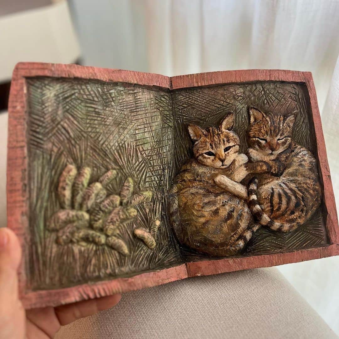 はしもとみおのインスタグラム：「絵本を開いたような、 アルバムの想い出の1ページのような木彫りのレリーフ。 レリーフを制作し始めて三年が経ち、立体彫刻とはまた違う味わい深さに制作していて暖かい気持ちになります。 この前棟方志功さんが版を彫っている映像をみましたが、あの気持ちに近いのかもしれません。 本の形をしているのもまた好きな部分で、きっと私は本がものすごく好きなのだなと。  レリーフは天気や風景や、彫刻では表現できないものも表現できるので、そんな世界線や物語も作っていけたらなと思っています。  #woodcarving #woodworking #woodsculpture #sculpture #relief #woodrelief #miohashimoto#animals #animalart #cat#book #bookart」