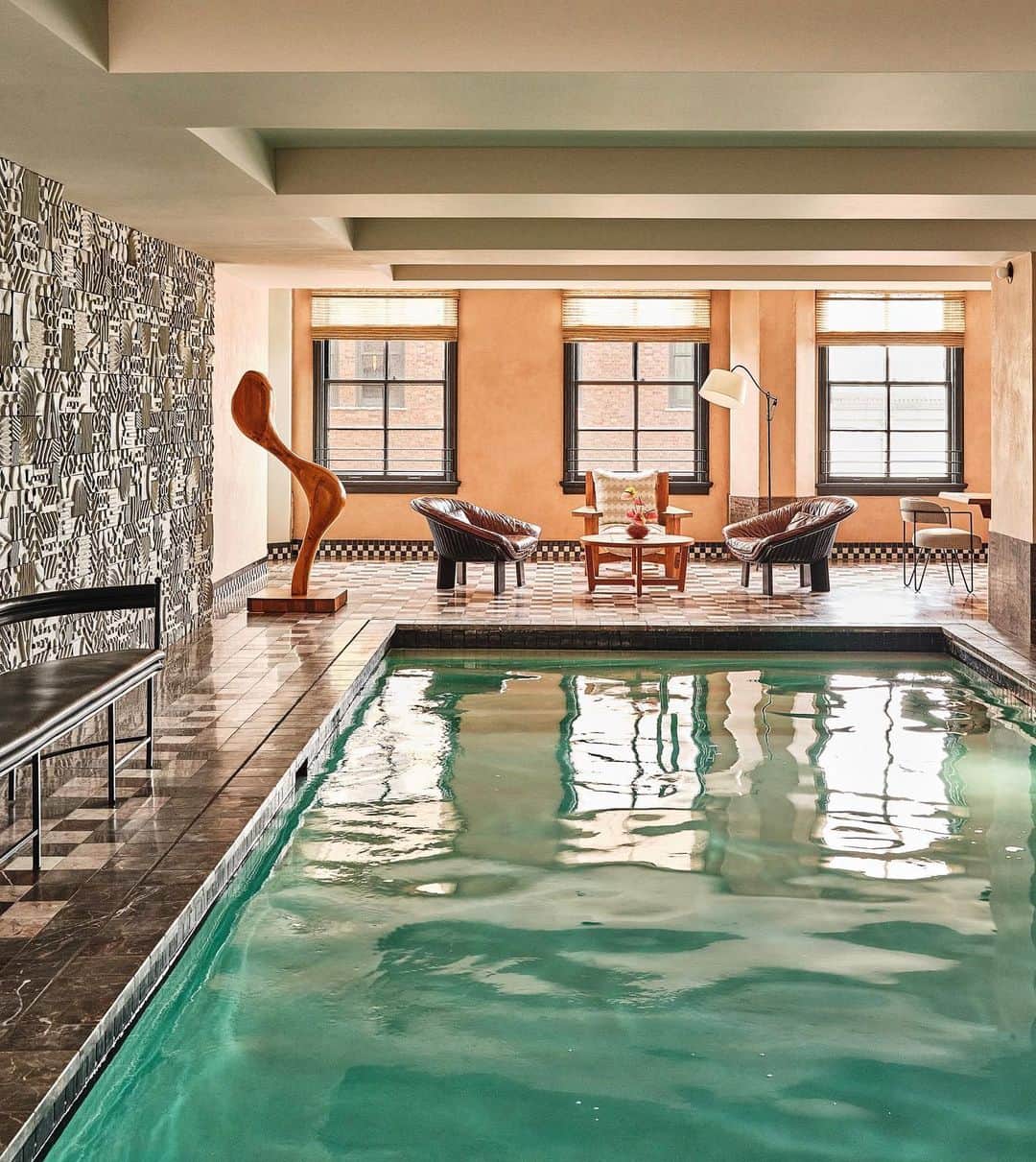 ケリーウェアスラーのインスタグラム：「TAKE THE PLUNGE. The dramatic pool suite on the seventh floor at the @downtownlaproper went through heavy refurbishment from its original design… dating back to when the building was a YWCA. A custom ceramic mural by Ben Medansky gives the space a sense of movement and cohesion with the pieces added, including a vintage wood sculpture by an unknown artist,  a pair of vintage Alky armchairs by Giancarlo Piretti, and a Gunilla Allard bench. XK」