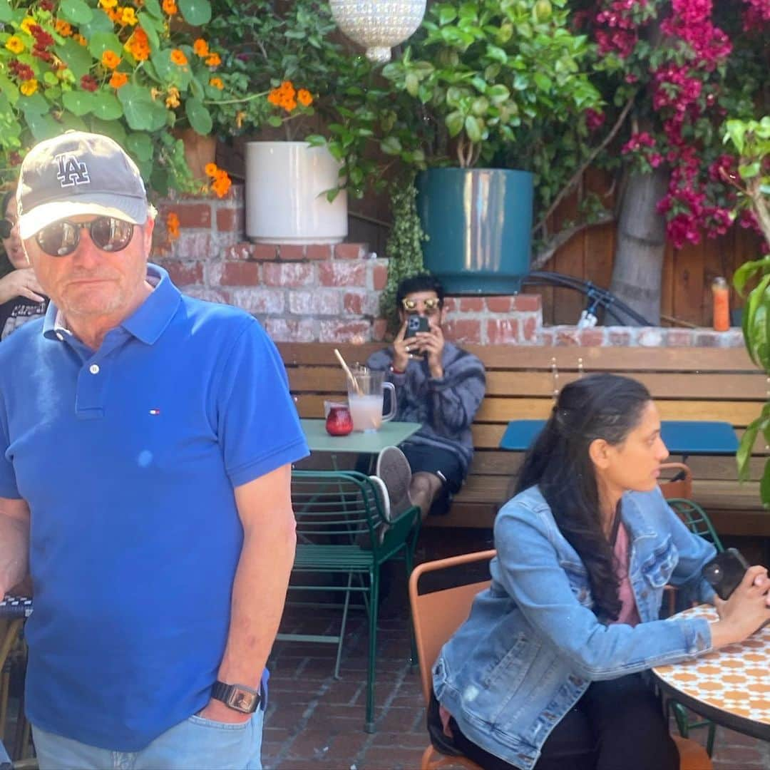 コール・スプラウスのインスタグラム：「Hark, do you see? Underneath the bougainvillea? The amateur magician cosplayer seated behind his solo margarita pitcher with the extra long straw. Watch as he makes his liver disappear. Don’t drink and duel, it reduces stealth. This should be an obvious tip, but I’ll admit it was a particularly beautiful day for an afternoon drinkypoo.  I sometimes wave at the person dueling me before I take out my weapon, to give them a little “hey I’m letting you know I see you.” If they still persist in the duel, then it’s on. However, when I waved, the man in blue waved back at me. Just a friendly interaction. Misjudged but friendly. Blue man and I had a connection, it was real. I felt it. And then when I pulled out my camera, he was disgusted (observe his expression). I think he must have assumed I was taking a photo of him, which would be incredibly strange. It’s so strange actually, I’ve dedicated this entire Instagram account to precisely how he felt in that moment. For a moment he was cole. I’m sorry blue man, you were a victim of friendly fire.   #cameraduels #abrakadasshat #rolereversal」