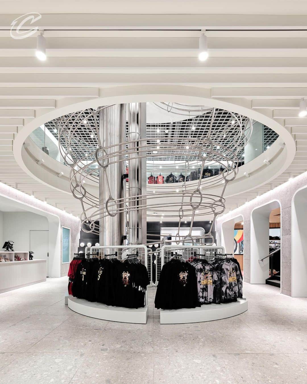 キャブスのインスタグラム：「✨CENTER COURT NOW OPEN✨  Curated for simplicity, @snarkitecture has created an elevated shopping experience for our fans that features both Cleveland Cavaliers and @monstershockey retail merchandise.  The Basketball Run, designed for the space by @snarkitecture, is a kinetic sculpture that hangs from the second floor ceiling and spans down the the ground floor. Custom white basketballs travel in a continuous loop along the rails, activating the space.  Take a look through our redesigned @cavsteamshop, Center Court.  📸: @seandavidson」