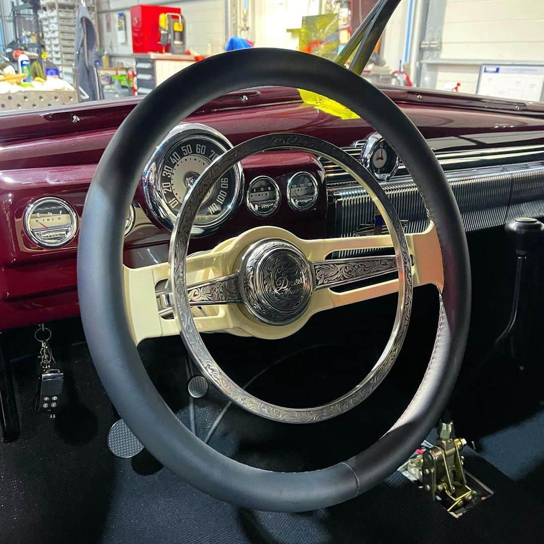 ウエストコーストチョッパーズのインスタグラム：「Steering wheel novella…  I know my shop West Coast Choppers is known predominantly for building motorcycles. We also build cars with an equal level of workmanship and detail.  Here’s some photos of that high level of detail that went into just the steering wheel on Greg Cooke’s ‘49 Merc.  Starting with a design plan inspired by early Porsche accessory Petri steering wheels.  A billet blank was CNC turned by Mike Curtis with the correct offset to not have to run a big adaptor.  WCC Machinist Anthony then cut all the windows and surfacing profiles.   Stainless Steel horn ring and button were machined and fit.  In-house Artist Matt created hand drawn artwork for the horn button.  Master engraver Jere Davidson hand relief engraved the horn button and ring.  Wheel was painted cream white color and covered with a hand stitched leather cover by Aaron at Innovative Rides.  Lots of steps and processes make for an amazing result. And a fitting tribute to Drew Cooke (Greg’s son) who unfortunately passed away during this build.  #jessejames」
