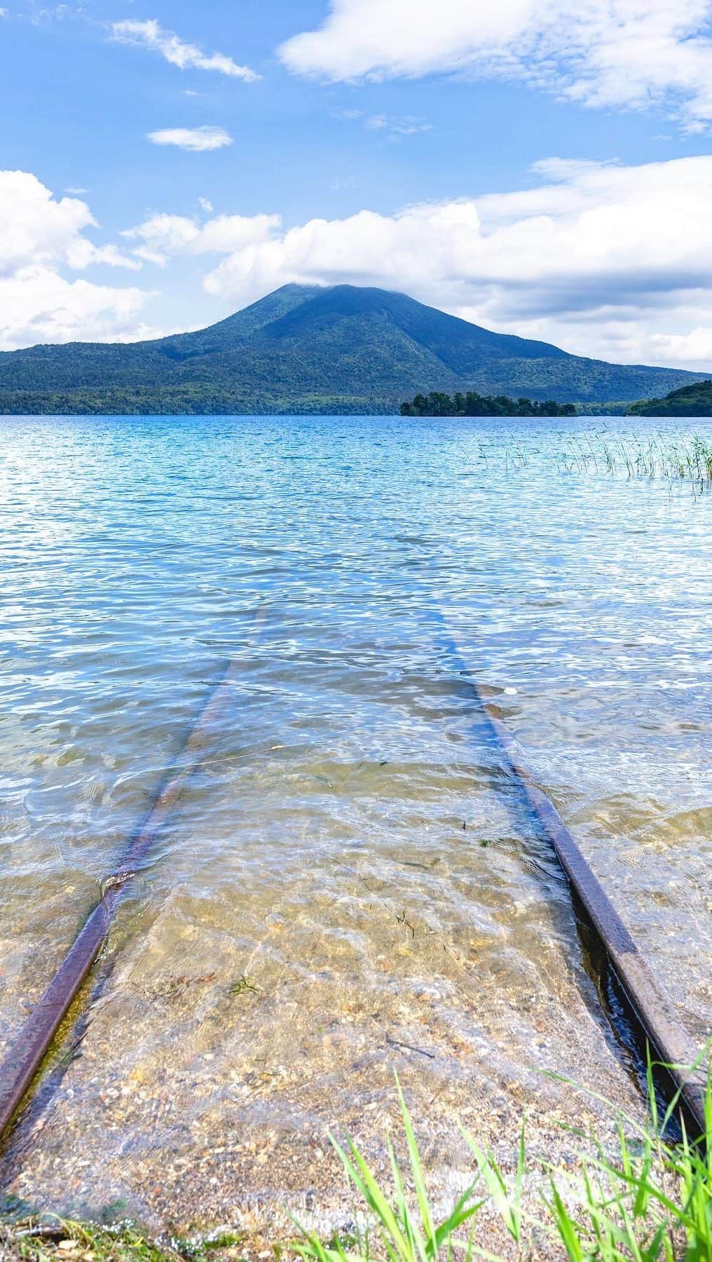 詩歩のインスタグラム：「📷 July 2022 📍北海道 阿寒湖 / Lake Akan, Hokkaido Japan 🏷️ #shiho_hokkaido   北海道の阿寒湖で、湖の中へと続く名もなき線路を見つけました。  静かに打ち寄せる波と青く透き通った湖水。草むらに隠れるように佇むその姿は、まるで異世界への入口のようでした。  Last summer I found a place at #LakeAkan in #Kushiro that looks like a scene from a movie #SpiritedAway . The quiet lapping of the waves and the clear blue water of the lake. It was like a gateway to another world.  ⚠ここは看板はありません。具体的な場所と地図は昨年アップしているので  #詩歩のくしろ旅 から探してください。船会社の事務所や機材があるので迷惑のかからないようにしましょう！  This is one of the places in Lake Akan where there are no signs. Please find the about place from #詩歩のくしろ旅 as it was uploaded last year. There are offices and equipment of the shipping company here, so let’s go sightseeing polite and quietly!  ©︎Shiho/詩歩」