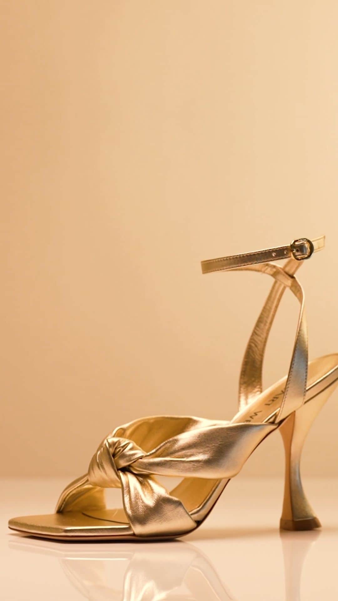 スチュアートワイツマンのインスタグラム：「Pick your PLAYA sandal, featured here in seashell leather, pistachio leather, gold metallic leather and light-wash denim. From its luxe, super-soft knotted detail to its sculptural 100-mm heel, this glam silhouette nods to the expert craftsmanship of our artisans in Spain. Find your favorite color on stuartweitzman.com. ​  ​#StuartWeitzman #PLAYA #PlayaLife」