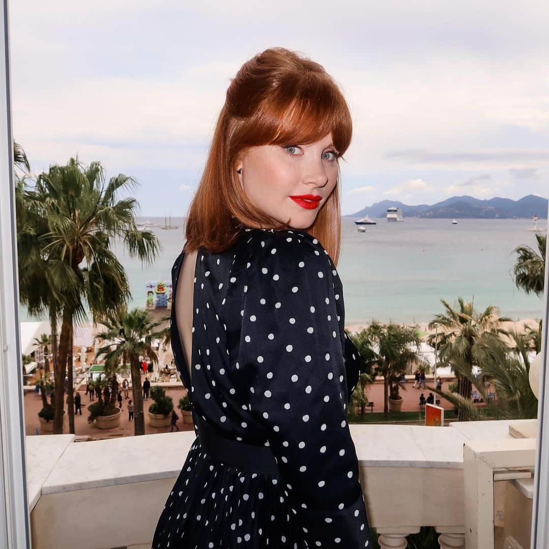 ブライス・ダラス・ハワードのインスタグラム：「Happy Cannes-iversary 😘⁣ #CannesFilmFestival ⁣ ⁣ Makeup: @karayoshimotobua⁣ Hair: @jennychohair⁣ Styled by Publicist Extraordinaire: @alex.schack ⁣ Clothes: @khaite_ny & @vitafede purchased secondhand from @therealreal ⁣ [ID: Giving a coy look over her shoulder, BDH wears a cutout black dress with white polka dots. She stands on a balcony that looks out to the glittering French Riviera]」
