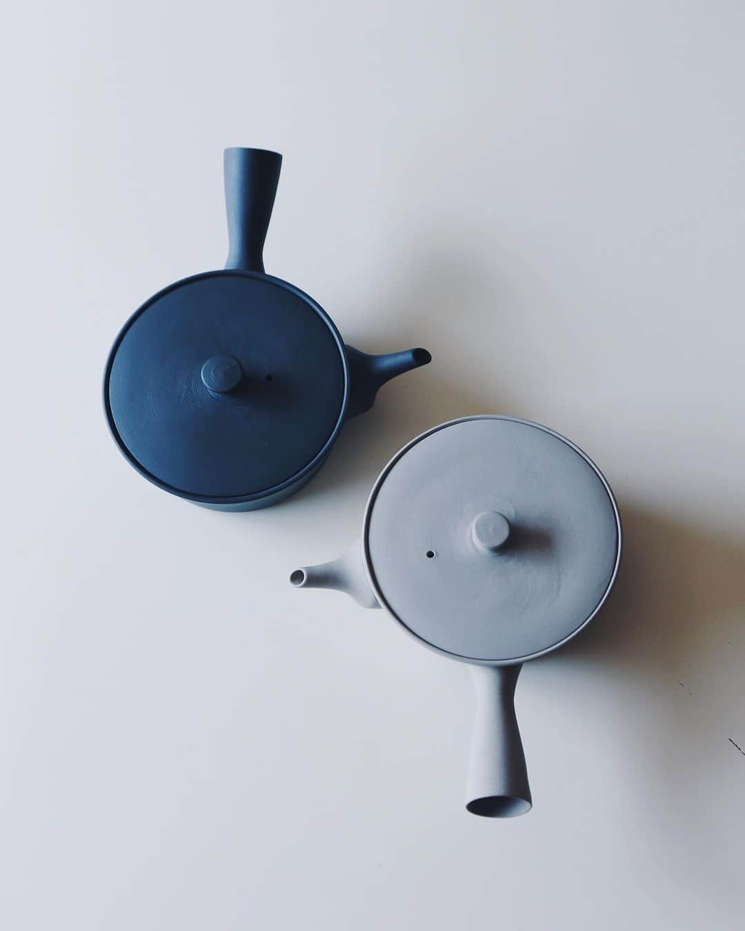 nostos booksのインスタグラム：「南景製陶園 @nankei_pottery の手掛けるのSenchaシリーズの急須は、本体も蓋もシンプルで直線的。こうしたかたちは焼成時に変形しやすく、陶器としてはとてもつくり難いそう。  釉薬のかかった磁器の急須はお茶の味をストレートに楽しむのに適していますが、 南景製陶園の急須は土の肌理に細かな凹凸があることでお茶の渋みを程よく緩和し、まろやかで美味しく変化させるという特徴も。  茶漉しは、昔ながらの共茶漉し。急須本体と同じ土で作られた茶漉しは、ひとひとつ職人が手作業で穴を開けています。  心を鎮めて、ほっと一息、深呼吸。  立ち昇る湯気のあたたかさを感じながらお茶を囲む時間は、自分や、まわりの誰かの心をそっと解きほぐしてくれるはずです。  オンラインストアへは商品タグをタップ◯  ----------  店舗情報はこちら @nostosbooks  ----------  #南景製陶園 #nostosbooks #ノストスブックス #祖師ヶ谷大蔵 #砧」