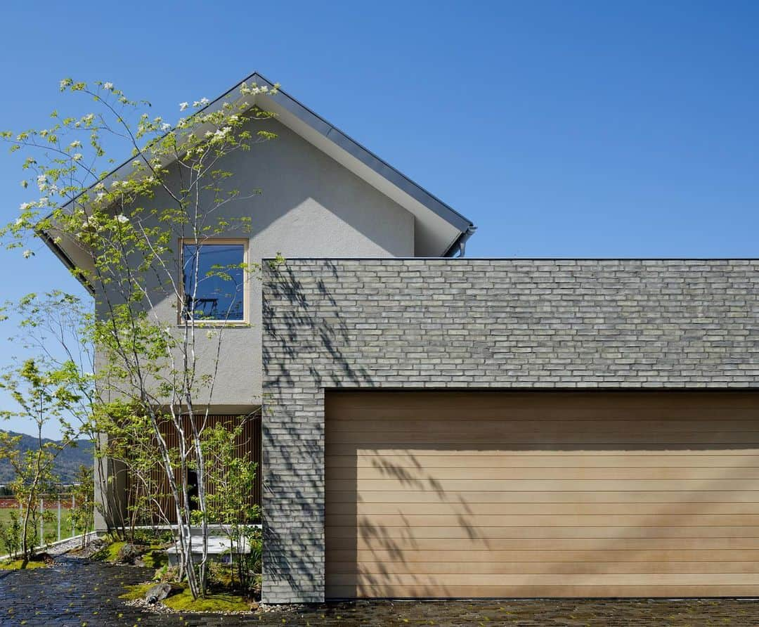 アイトフース | 北欧住宅｜注文住宅｜広島・岡山・山口さんのインスタグラム写真 - (アイトフース | 北欧住宅｜注文住宅｜広島・岡山・山口Instagram)「外壁にはシラスそとん壁、ガレージ部分にはデンマーク煉瓦を採用したお住まい。 窓、ガレージ扉、玄関扉には木を用いるなど、歳月とともに風合いを増していく普遍的な素材のみを使用し、自然素材で構成されたからこその上品さが感じられます。 . ---------------------------------- YouTubeにてこちらのお住まいの ルームツアーを公開しております！  🔍「アイトフース」で検索 ---------------------------------- #aitohus #アイトフース  . . . . . アイトフースは創業時(1995)より、住環境先進国北欧の「人」が中心という考え方から生まれるデザインをお手本とし、同時に古来「庭屋一如」という日本建築様式を大切に、和と北欧を融合させた住宅設計施工を行なっています。 . 家を好きな場所にすると 人生は楽しい。 アイトフースの住まいが 家族にできること。 . 温熱環境によるストレスがなく、家事労働を1/2以下に軽減し、自然を身近に感じられる、そんなゆたかな暮らしをご提案しています。  . #和と北欧 #ジャパンディ #自然素材の家 #建築 #広島注文住宅 #岡山注文住宅 #広島新築 #岡山新築 #塗り壁 #そとん壁 #外観 #玄関アプローチ #ガレージ #ガレージのある家 #木製サッシ #施工事例 #住宅デザイン #housedesign #modernhouse #scandinavian」5月19日 18時47分 - aitohus