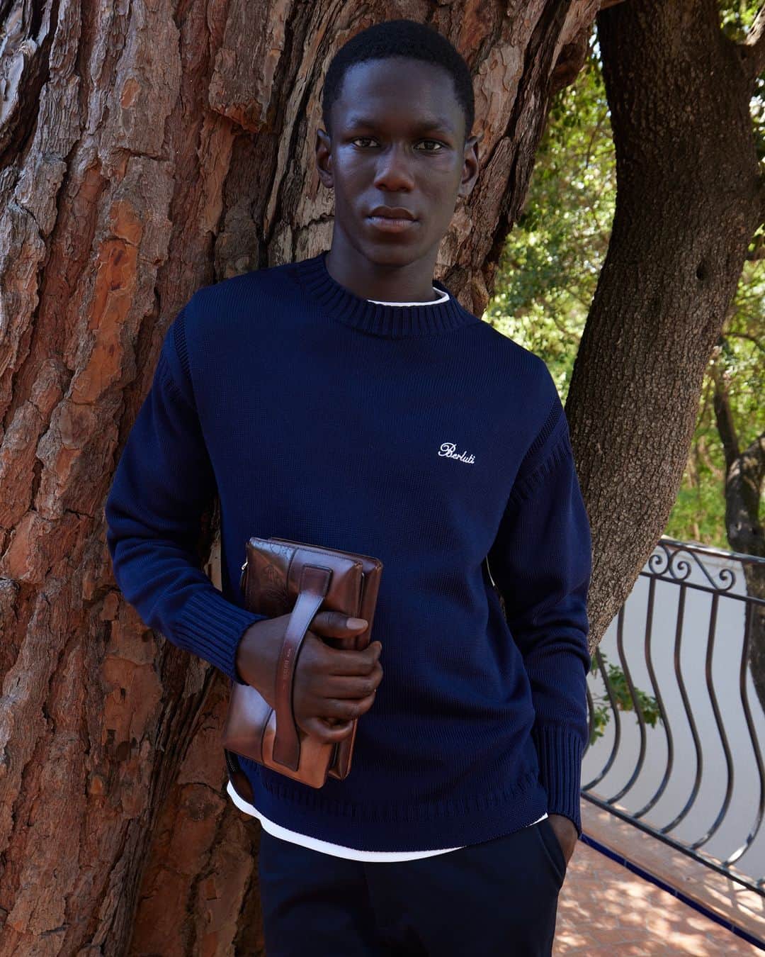 のインスタグラム：「- THE SILHOUETTE BY #BERLUTI -   A cool vibe meets a nonchalant attitude to create the Summer 2023 look: decorated only with a subdued Berluti logo, a minimal cotton sweater is paired with the new Terzio pouch in patchworked Venezia leather to bring extra depth to the patina.   Now available online and in-store.   Styling by @virginiebenarroch  Photography by @anthonyseklaoui」