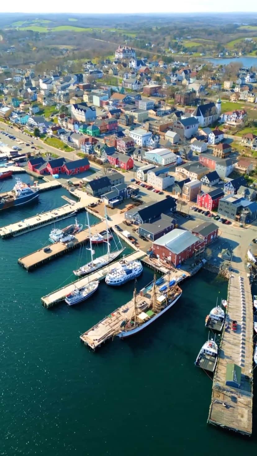 Explore Canadaのインスタグラム：「Do you prefer Lunenburg at day or night? Tell us your vote by dropping a ☀️ or 🌙 in the comments below!   Lunenburg is not only a must-stop for its colourful waterfront, but it’s also one of only two urban communities in North America designated a UNESCO World Heritage Site.   The harbour-side streets are lined with unique shops and award-winning restaurants that blend with the well-preserved and colourfully painted historic homes, much of it like a living museum from the 18th century.   📷: @jakeescapes 📍: @visitnovascotia   #VisitNovaScotia   [Video description: An aerial view of the port in Lunenburg, Nova Scotia first in daytime, then at night as the sun sets turning the sky pink. The port shows various docks on the water lined with boats, and coloured buildings that stretch back into the green landscape behind the town.]」