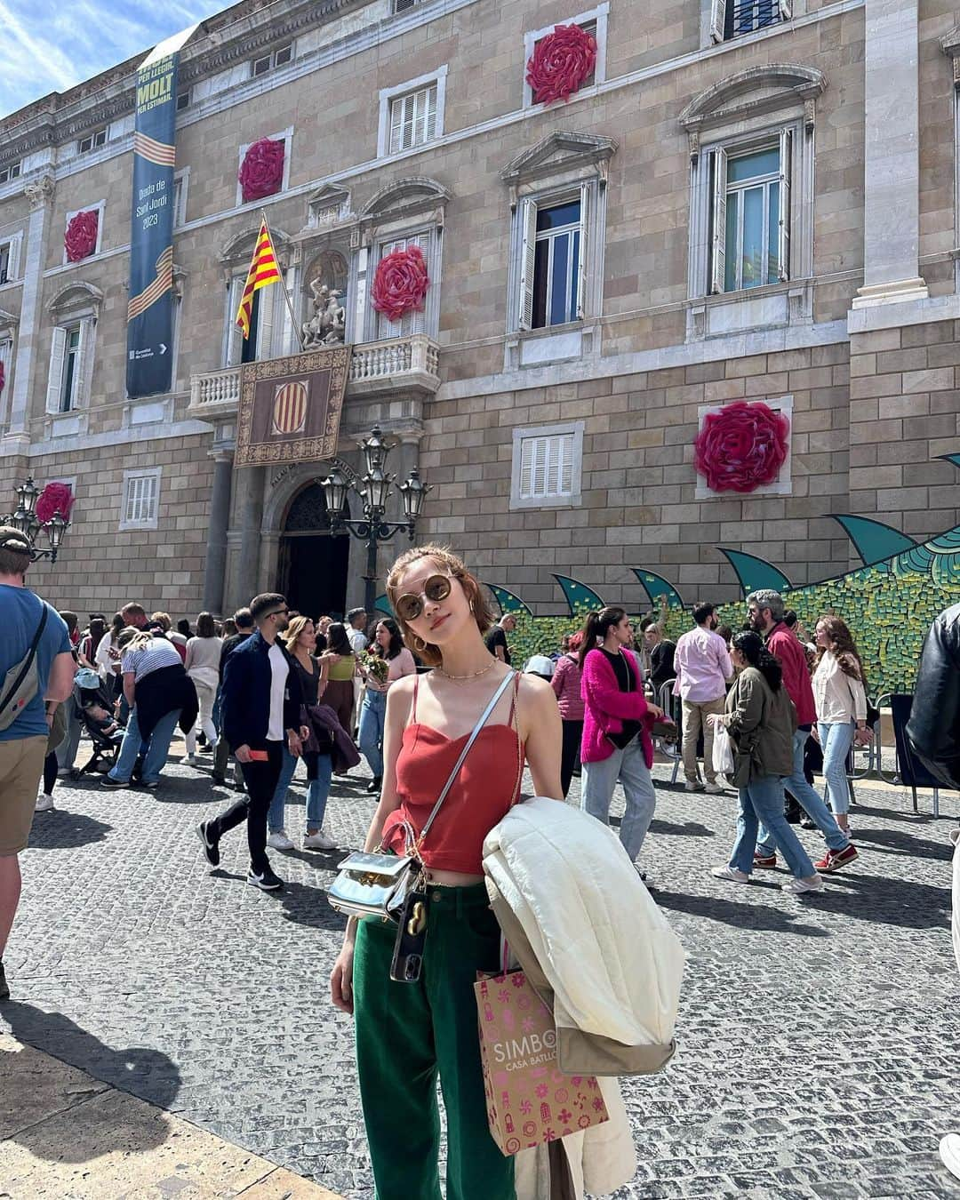 真鈴のインスタグラム：「バルセロナ旅行記　 🌹再開🌹  写真は カタルーナ広場 この日はちょうど本と薔薇のお祭りの日で街中に 🌹が沢山人👬も沢山！ 途中美味しそうなチュロス屋さんがあったの、チュロスはスペイン発祥だから絶対食べようって日本にいる時から話してたんだけど結局行かなかったんだよね…💦 お腹全然空いてなくてなぁ😮‍💨 けど、もう歩いてるだけで楽しくて道端でオペラ歌ってるオバチャンとか居てみんな盛り上がっててそうゆう陽気な感じが大好きだ🥰  そしてスペイン在住のアイさん🐕🙋‍♀️❤️にオススメしてもらった カサ・バトリョ　 Casa Batlló   薔薇で飾り付けされててとっても可愛かったし流石ガウディ、内装もとっても面白かったんだけど帰り際はひたすら階段降りなきゃいけなくて暑いし水持ってたからよかったけどおばあさん達とかもう途中で止まって息切れしてて本当気の毒だったー😩夏場に行く人は絶対水持ってた方がいいわ💦 そしてカサバトリョで買ったトカゲ🦎ちゃん❤️ 旅のお守りみたいな気分で購入♩ 帰ってきてからもこのトカゲちゃん見ると楽しい気持ちになるよ🥰  そしてそして念願の サグラダファミリア〜 Sagrada Família 1度は見てみたいと思ってたから地下鉄の階段登って振り返ったらドドーンとサグラダファミリアが見えた時は感動🥺✨ なんだかとっても神秘的だった🕊  ただ1番いい顔したのはあっつくてお祭りのせいでお店全然やってなくて奇跡的に入れたホテルのレストランで食べたサラダを食べてる時かなぁ…🤤 すっごく美味しくて 沁みたわぁ… 確かマジェスティックホテルってとこだった気がするよ。 まだまだつづく〜はず〜  #バルセロナ旅行 #バルセロナ観光  #ootdfashion  #旅行コーデ  #スペイン旅行 ✈️」