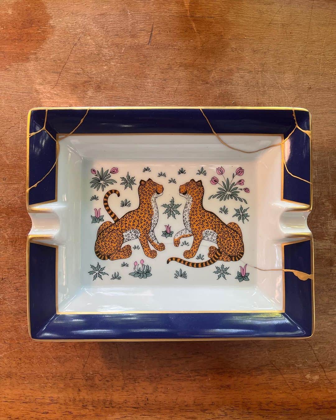 稲木ジョージのインスタグラム：「Kintsugi is the art of repairing a broken object with urushi (lacquer) and finishing it with gold powder. The brokenness becomes the design, turning it into an art form. The same concept can be applied to ourselves. Cherish your flaws because they make you who you are ♥️. I'm happy that my broken Hermes vintage ashtray is back, and it's even more beautiful now 🫶. 金継ぎは割れた陶器を漆で継ぎ、金粉で仕上げることを指します。割れ部分が「景色」となり、美しくデザインに変えてしまうことです。こちらのビンテージのエルメス灰皿が自分のドジで割れてしまい、金継ぎ師にお願いをして金継ぎの線をデザインしました。金継ぎの原点である「鎹」を銀で施し、パンクに。 金継ぎのフィロソフィーは我々にも当てはまります。人間必ずしも内面外面ともに欠点があります。自身で認め、自愛することによって、欠点が愛嬌となりかわいくなるかもしれませんよ🤭」