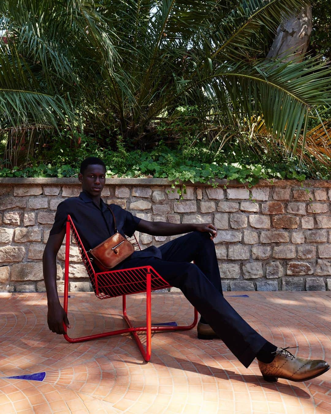 のインスタグラム：「- THE SILHOUETTE BY #BERLUTI -   When it comes to the Summer 2023 collection, subtlety is the mot du jour. Black trousers match with a short-sleeved cotton-and-silk shirt with a same-tone Scritto motif. Accessories highlight leather and patina know-how, from the iconic Alessandro lace-up shoes to the new Nino Duo cross-body bag.   Now available online and in-store.  Styling by @virginiebenarroch  Photography by @anthonyseklaoui」