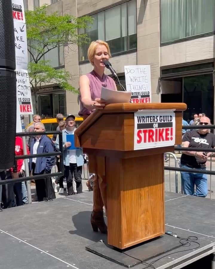 シンシア・ニクソンのインスタグラム：「Today at @WGAEast’s #RallyAtTheRock to support my writer colleagues who are fighting for a fair and honest contract. As the sign behind the podium said, it’s time to do the WRITE thing! 📝  Swipe to the end for my tribute to some of the greatest (and most apropos) lines of all time! #WGAStrong」