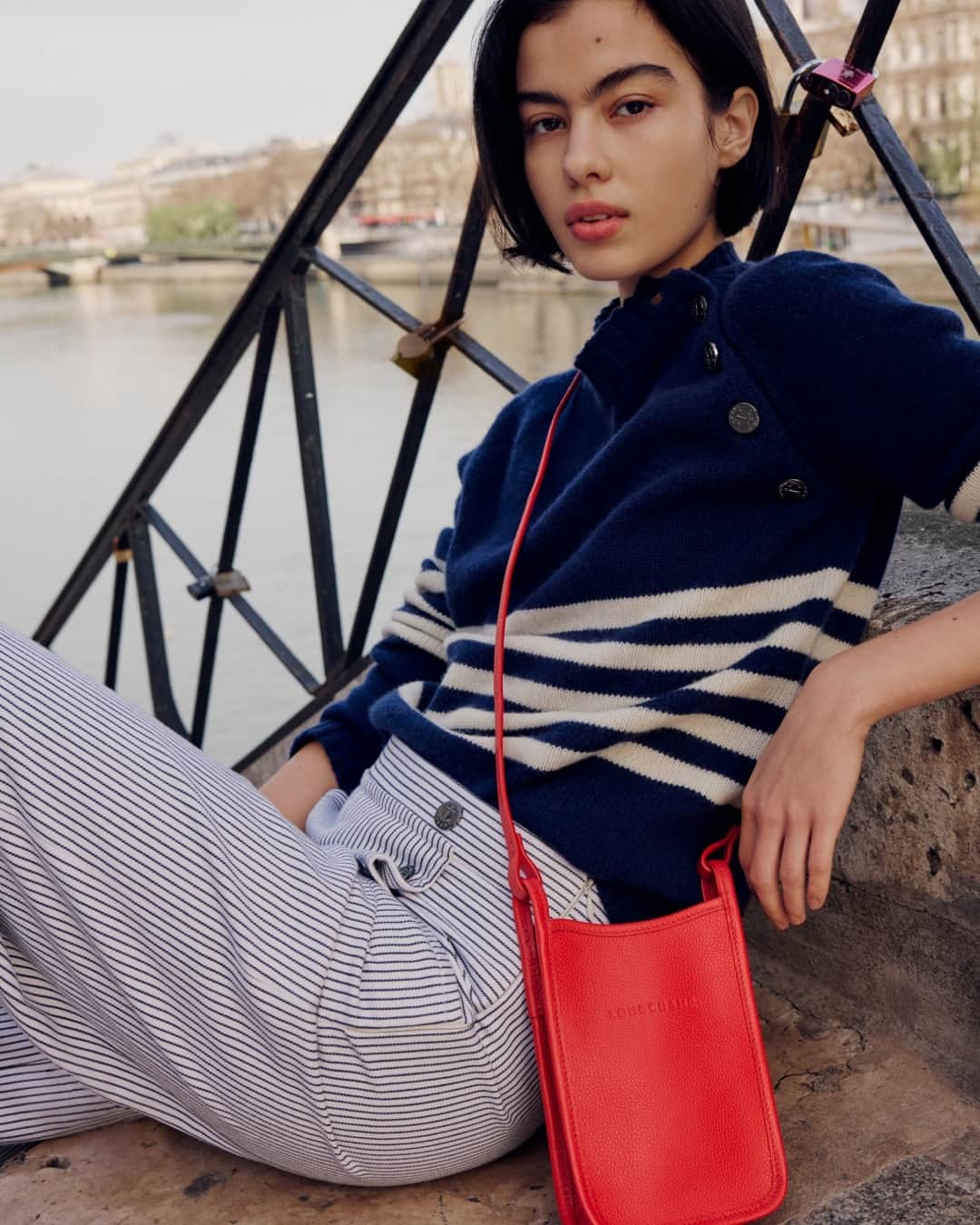 Longchampのインスタグラム：「A great way to start the day: waiting by the Seine while friends are on the way. _________________________________________  Une bonne façon de commencer la journée : flâner sur les bords de Seine en attendant ses amies.  Photographer: @louisemeylan Stylist: @leameylan  Hair stylist: @cyril.lanoir  Make-Up artist: @manu_kopp  Model:  @vivicazotti  #LongchampFoulonne #LongchampFW23  #parisian #frenchstyle #redbag #paris #newcollection #red #lifestyle」