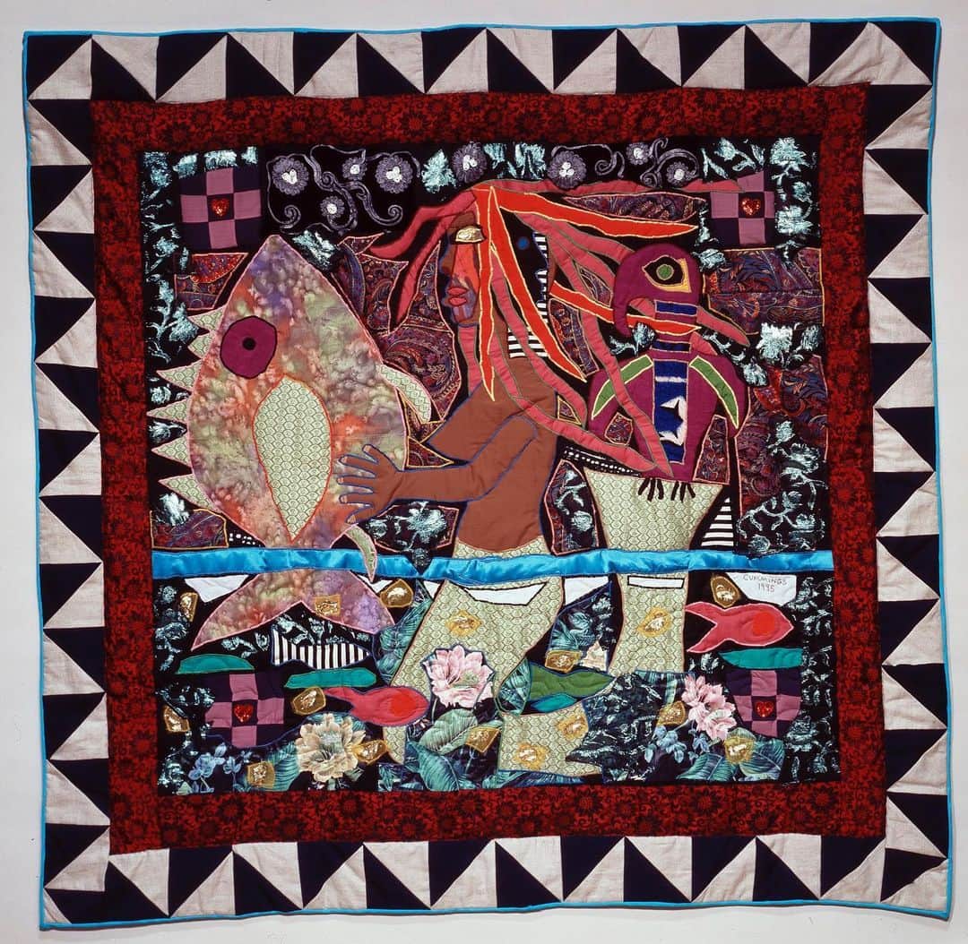 のインスタグラム：「Look at this stuff. Isn’t it neat?   Dive in as we uncover the wonders of this quilt by artist Michael Cummings. Inspired by a Yoruba goddess, Yemaja, a deity of love, faith, and purity, she can transform herself into a human when visiting land. Cummings has used the images of the parrot and fish to represent Yemaja’s power over both land and sea.   Like Ariel’s grotto, “Haitian Mermaid #2” is filled with a wide variety of materials, including beads, sequins, and hand-dyed and antique fabrics. Cummings has combined bright colors with dark tones of blue and black to suggest a tranquil night scene.    Image from @americanart:  Michael Cummings, “Haitian Mermaid # 2,” 1996, machine pieced, quilted, and appliquéd commercial and hand-dyed cotton, synthetic and antique fabrics, found objects, sequins, and beads」