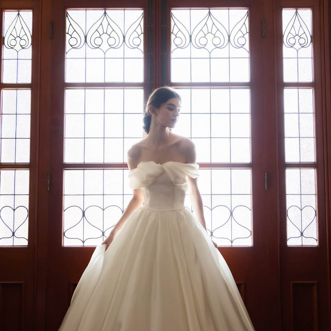 TAKAMI BRIDALさんのインスタグラム写真 - (TAKAMI BRIDALInstagram)「*  Ciel / シエル  花言葉が「愛情、固い約束」のアサガオの蕾がゆっくりと花ひらく様子をドレスに表現しました。ネックラインは、蕾のねじれがほどけるようなイメージのツイストドレープ。ダーツを組み合わせた3Dスカートは、アサガオが花ひらいたようなシルエットです。立体感が特徴のクチュールテクニックを要するデザインで仕上げました。 アサガオのツルが固く結ばれながら伸びるイメージから、おふたりの深い結びつきを象徴します。明るい光に包まれ、幸福感が香りたつドレスです。  ※バックリボンは取り外し可能です。」5月26日 17時45分 - takamibridal_costume