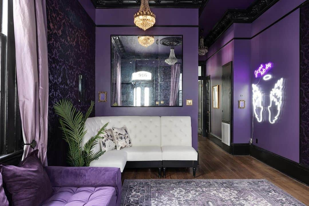 クリスティ・ルーカジアックのインスタグラム：「Welcome to the Voodoo Lounge. 💜🖤  On the Sinners side of the house, this open concept room was designed to pay tribute to the dark legends of New Orleans, such as Marie Laveau, Voodoo Queen, and The LaLaurie Mansion, inspiration for American Horror Story: Coven. We intentionally kept the floor space open for your party to have room to dance, play a wicked game of Truth or Dare or simply to take the best group shots before a legendary night out.  And the neon angel wings give you a perfect backdrop for your photos to let everyone know you just might “Get Your Halo Dirty”. 💜🖤😇  What’s your fav part of the room? And does “sinner” resonate with you?? 💜🖤  Swipe 👉🏻 for the “before” to see the kitchen with the serving window and, um, UNIQUE loft before the renovation.」