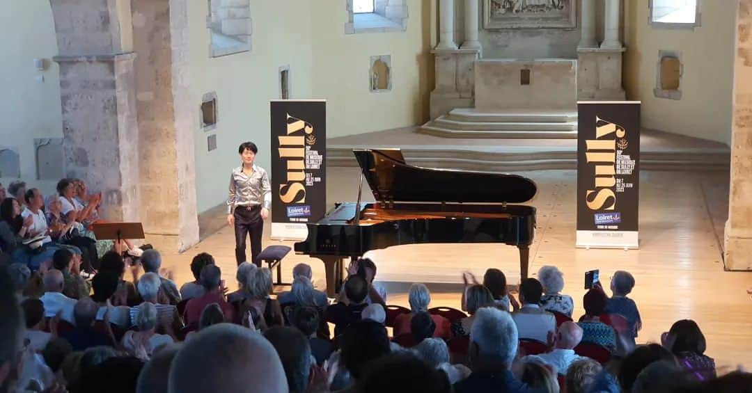 福間洸太朗のインスタグラム：「Un grand honneur de clôturer le 50e Festival de Musique de Sully et du Loiret. Merci à toute l'équipe du festival et au public❣  Photo 4 : avec Claude Henry Joubert (commentaires)  光栄にも、今年第50回となるシュリー・シュル・ロワール音楽祭の最終公演でリサイタルさせていただきました。8年前の会場はシュリー城でしたが今回は素敵な教会。満席のお客様からスタオベ拍手いただき、胸が熱くなりました。🥹  #FestivaldeMusiquedeSullyetduLoiret #SullysurLoire #Mozart #Chopin #Rachmaninov #Piano #pianorecital #ピアノ #シュリ―シュルロワール #音楽祭 #モーツァルト #ショパン #ラフマニノフ」