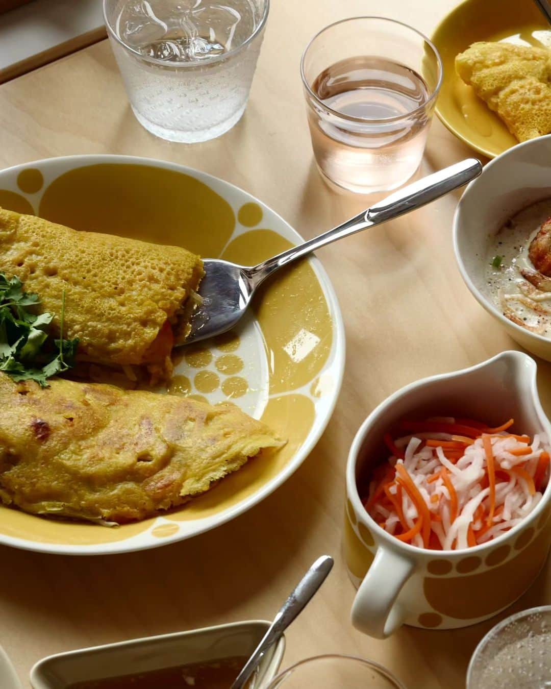 Scopeさんのインスタグラム写真 - (ScopeInstagram)「週末はベトナム料理にて #スンヌンタイのブランチ しましたから長いんだけど 感じた諸々を書いてみます。  僕は料理を盛り付ける前に どの料理をどの食器に盛り付けるか？ 食器をテーブルに並べてみることから 始めます。食器を入れ替えつつ、 そのセットが完成するまで組み替え、 入れ替えを続け、今回はコレでいく！ それが最後の写真です。  スンヌンタイに Teemaホワイト＆ハニーを混ぜると イイ感じにまとまりますし、夏は Teemaホワイト＆ハニーが映えます。 そしてツンドラのクリアなツブツブ 装飾がスンヌンタイとマッチして 想像以上によかった！ナイスと思う！ だからウォーターグラスに Tundraタンブラー 290ml クリアを 選び、バランスをとってワインは Bellman ウィスキーにしましたら 使うにも良いバランスでした。  バインミーは名古屋に新しくできた @banhmixinchao.jp で買ってきて 置いただけながら、オーバルプレート 25cmと、バインミーの形状はなんだか マッチして可愛らしかった。嚙む力も 鍛えられアゴ筋トレにもなって衰えを 少し克服した気分です。そのサイドに Teemaシリアルボウルとプレート15cm のハニー＆ホワイトを添えてます。 この組み合わせは安定配置です。  センターにはバインセオを盛り付けた Sununtai プレート26cm、そのタレは Teemaミニサービングセットリネンの 三角型に入れたのが超良かった。 そしてスタッフ松尾が激押ししている Savoniaケーキリフター、そこまで 大きくなくて見た目のバランスもよく 取り分けに使うと便利からのナイス。 1つあるといいのは確かです。  ガイヤーン＆ミントは Teemaプレート23㎝リネン を使いました。  今回リネンは2つ加えていますが、 あまり増やすと夏感が薄れるので 少しだけ足すのが良いみたい。  ただ午前中から飲んで調子でると 午後から寝てしまって気づけば夕方 オーマイゴッドファーザー降臨！ となりますのでご注意を。 でも、とても美味しかったです。  何かしらの参考になればとツラツラ 書いてみまスタミナ弁当。  #scope_japan #スコープ計画018 #スンヌンタイのブランチ #arabiafinland #sunnuntai #スンヌンタイ #iittala #イッタラ #teema #ティーマ #北欧食器 #北欧雑貨 #tundra #ツンドラ #ベトナム料理 #バインミー #バインセオ #ガイヤーン #アラビア食器 #ブランチ」6月26日 15時44分 - scope_japan