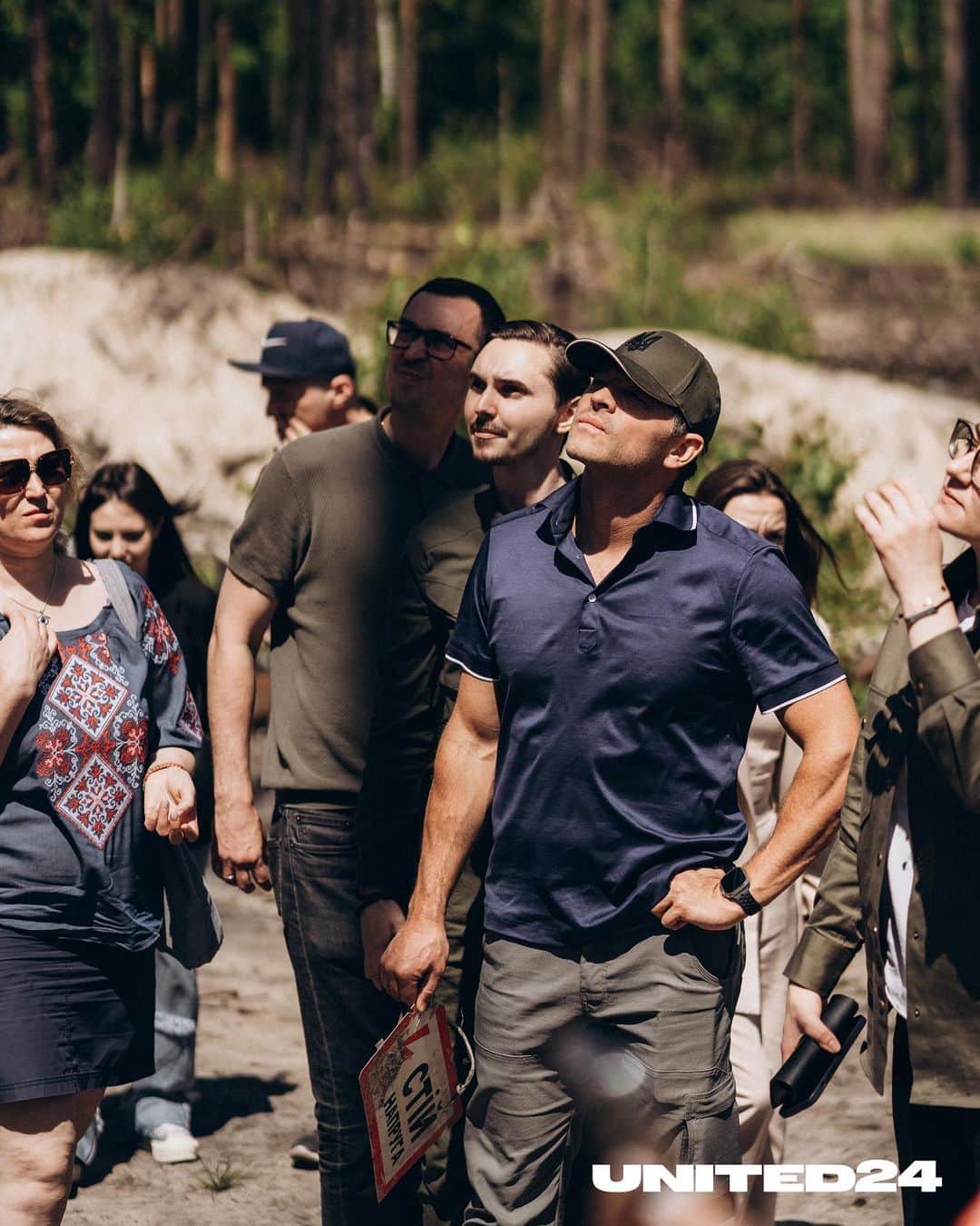 ミーシャ・コリンズのインスタグラム：「This is what Irpin forest looks like. Just 26 kilometers from Kyiv. It was occupied by the russian army during the first month of the war. 15,000 russian soldiers, ammunition depots, and artillery stations took part in the shelling of  Irpin and nearby villages.  The Ukrainian military liberated Kyiv Oblast at the end of March 2022, but the forest was partially demined only 2 weeks ago. Only one path is walkable, only when accompanied by de-miners, with little room for maneuvering. Our ambassador Misha Collins, and First Deputy Prime Minister of Ukraine, @svyrydenko.official , were the first to visit this once-inhabited place.  “In Ukraine, there are thousands of square acres of land contaminated with landmines. Many of them are on agricultural land, but they are also found in forests, on roads, and in homes, in children's toys, pianos, and refrigerators. The humanitarian demining operation across Ukraine is a complex and large project. I have worked with @gilesduley and the @legacyofwarfoundation in Laos for the last couple of years. Where the demining program has been going on since the 70s. However, even today, tragedies happen there every day — children lose limbs because of mines. This will be a massive problem for Ukraine for a very long time. But we can save tens of thousands of lives by implementing the demining program as quickly and efficiently as possible," said Misha Collins.  Support Ukrainian deminers and Misha Collins' fundraiser for demining vehicles.  #united24 #thepoweroffreedom   Так виглядає ірпінський ліс. Всього за 26 кілометрів від Києва. В перший місяць війни його окупувала російська армія. Тут розміщувалися 15 000 військових, склади з боєприпасами та артилерійські установки, з яких обстрілювали Ірпінь та прилеглі села.   Українські військові звільнили Київщину ще наприкінці березня 2022-го, але ліс частково розмінували тільки два тижні тому. Ходити тут можна лише однією доріжкою, нікуди не звертаючи, і тільки у супроводі саперів. Наш амбасадор, актор Міша Коллінз, разом із першою віцепрем’єр-міністеркою України Юлією Свириденко стали першими, хто відвідав це колись живе місце.」