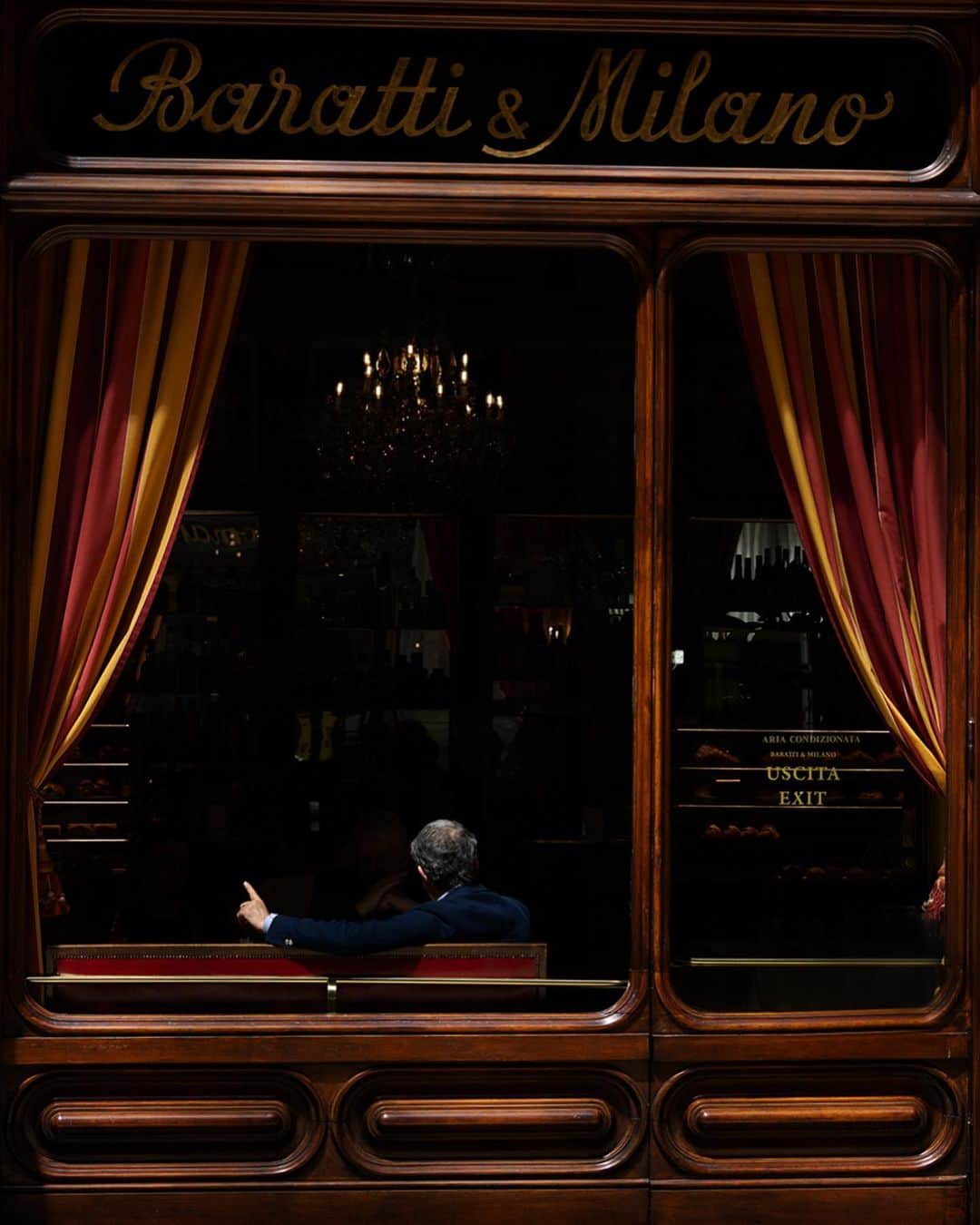 スコット・シューマンのインスタグラム：「The dramatic light, the curtains and the darkness of the caffè work together to  create the stage for this businessman to perform! @caffebarattiemilano in Torino」