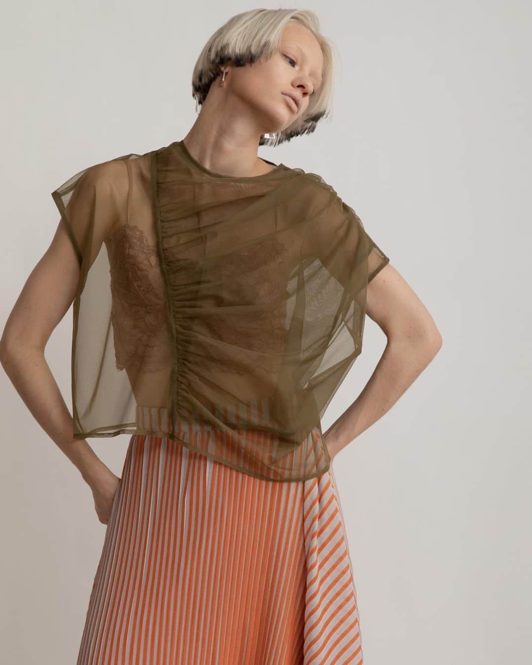 AULA AILAのインスタグラム：「【2023 HIGH SUMMER COLLECTION】  TULLE GATHER TOPS SET COLOR KHAKI×OFF SIZE 0 ¥16,500  ナイロンソフトチュールのトップスと、スリーブレスのカットソーがセットになったアイテム。 チュール部分は、ふんわりと体を包み込むように、アシンメトリーに寄せたギャザーを重ねて、透け感がありながら立体感のある表情に。 単品でワンピースやお手持ちのトップスに重ねて着まわすのもおすすめです。  STRIPE PRINT PLEATS SKIRT COLOR ORANGE×LT.GRAY SIZE 0/1 ¥23,100  細いプリーツとストライププリントの加工を施したオリジナル生地をレイヤードしたスカートです。  内側スカートは左裾にスリットが開いたタイトラインで、表スカートは広げると長方形になるデザイン。 プリーツとストライプの縦柄効果が、造形的でシャープな印象のスカート。  ✔️AULA AILA OFFICIAL WEB STOREにて HIGH SUMMER COLLECTIONアイテム展開中！」