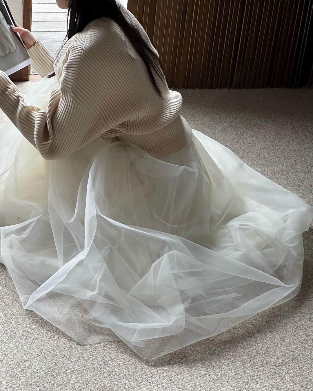 AICOのインスタグラム：「23AWPREORDERE ITEM <VOLUME LONG PANIER SKIRT> パニエをイメージして作成したボリュームスカートです。繊細なチュールを4層に重ね、ボリューム感のあるシルエットに拘りました。内側のチュールを外側よりもハリ感のあるチュールにする事で、表は柔らかな印象にみえながら、ボリューム感を出しています。ベルト部分は別素材にしJステッチ仕様にする事で甘すぎない印象に仕上げました。  <V NECK DOLMAN KNIT TOPS> ドルマンの様なゆったりとした袖周りとシェイプしたウエスト周りが女性らしい抜け感のあるシルエットです。上品な深さのVネック明きで少し抜いて着用しております。袖口は細めなので、たくし上げても着て頂けます。ウエスト周りがスッキリしているのでボトムにインがしやすくなっております。中肉のコシのあるリブ編みで仕上げ、モードなフォルムをキープしつつカジュアルに着用して頂けます。ウールが入っていない為、素肌に着てもチクチクせずに肌触りも良い糸で仕上げています。 #clane#clane23awpreorder」