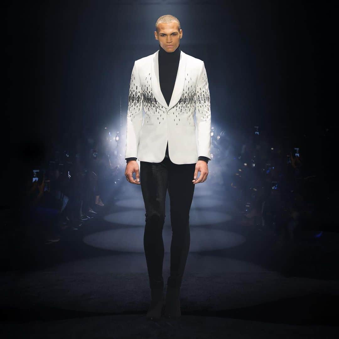 ジュリアンマクドナルドのインスタグラム：「Commanding the audience with an irresistible allure, the celestial Adonis @teyteyparx captivates the runway in a JULIEN MACDONALD bespoke menswear wool-tailored tuxedo jacket with a Duchess Satin lapel, finished with rectangular 3D hardware embellishment with hand-cut plexi, layered with faceted rectangular silver studs over a cashmere turtleneck and stretch velvet tailored trousers.  Big thank you to all who contributed to a successful JxG AW24 show  Styling: @karlplewka Makeup: @wendyrowe Hair: @sammcknight1 Nails: @glitterbels Shoes: @charkviani Belts: @jivomir.domoustchiev Tanning: @cocoandeve Production: @mybeautifulcity Movement Director: @officialroyston  Music: @djsmokinjo Casting: @angusctmunro PR: @purplepr Official Sponsor: @weshopsocial」