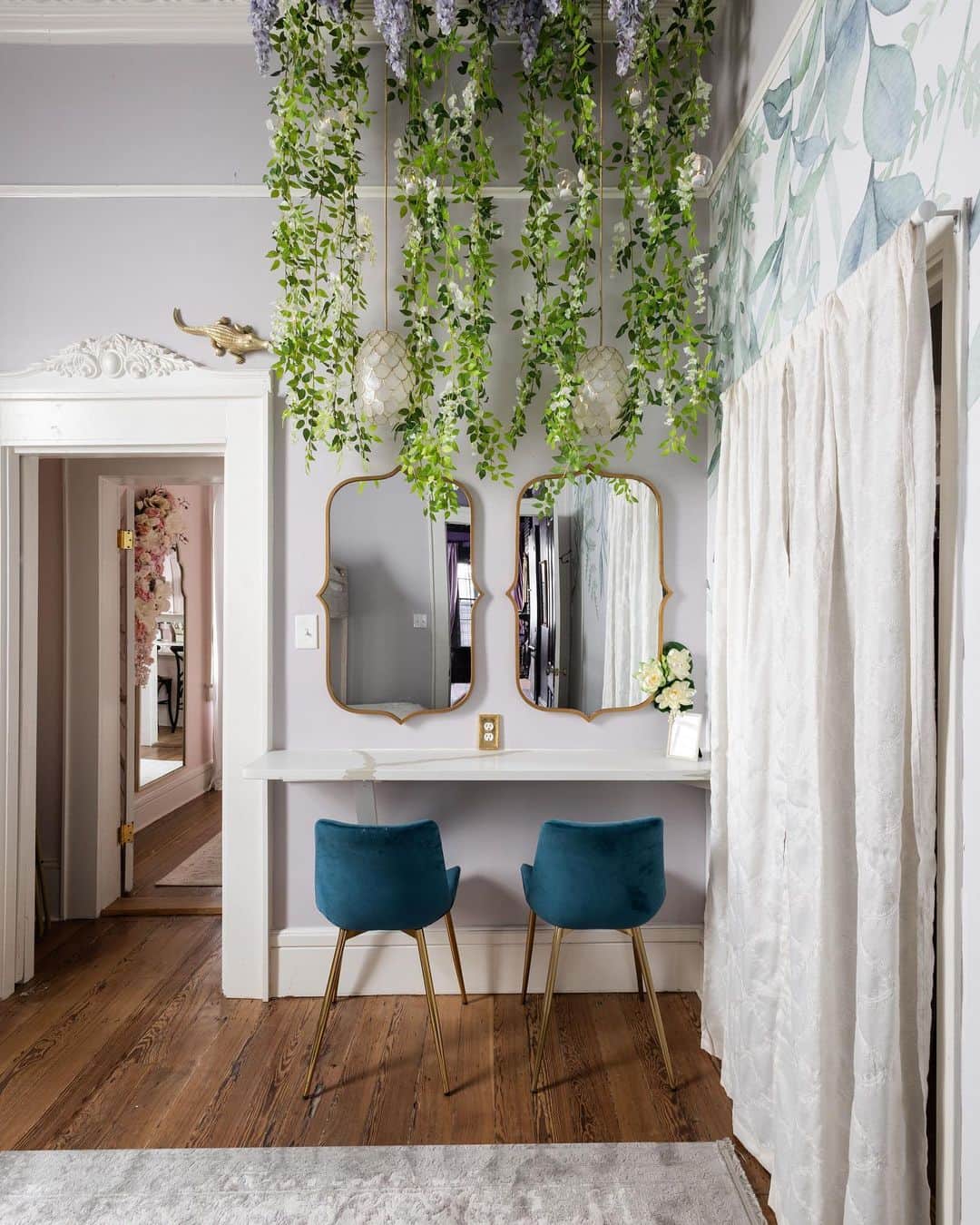 クリスティ・ルーカジアックのインスタグラム：「Welcome to the Bayou Bedroom. 💜  Inspired by the famous Louisiana bayous, this bedroom sleeps four and features a glam station with dripping wisteria and twinkle firefly lights. ✨ ✨  We also have local art of magnificiant trees dripping in Spanish moss, a vine wall and even a little gator to keep you company. 🐊   To connect this room (and front of the house) to the back apartment, we cut a pocket door in the wall and made a little transition hallway to pass from the “sinners” to the “saints” side.  We repurposed a closet door to be the pocket door to keep the integrity of the original doors in the house. 💜🖤💗🤍  Would you sleep here? Check out the link in my bio to book your stay. 😴」