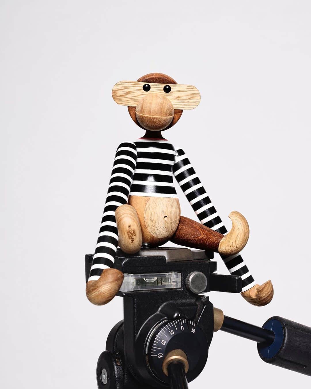 マッツノーガードのインスタグラム：「At Mads Nørgaard – Copenhagen we are proud to have the chance to dress the monkey. In collaboration with @kaybojesen_denmark the monkey is now wearing our classic #101 t-shirt. The monkey in a painted t-shirt comes in two variants: the original #101 in white with black stripes from 1967 and a new version in black with white stripes, both with red neckline. We call the new version KAY and has put it into production in a sewing room in Korsør (DK). The new KAY t-shirt is exclusively available in @norgaardpaastroget @madsnorgaardberlin @madsnorgaardaarhus and at madsnorgaard.com.    The monkey is produced in FSC®-certified teak and limba wood and comes in three sizes: S (H: 18,5 cm), M (H: 28 cm) & L (H: 47 cm). Every figure is created by hand. No two of them are alike.」