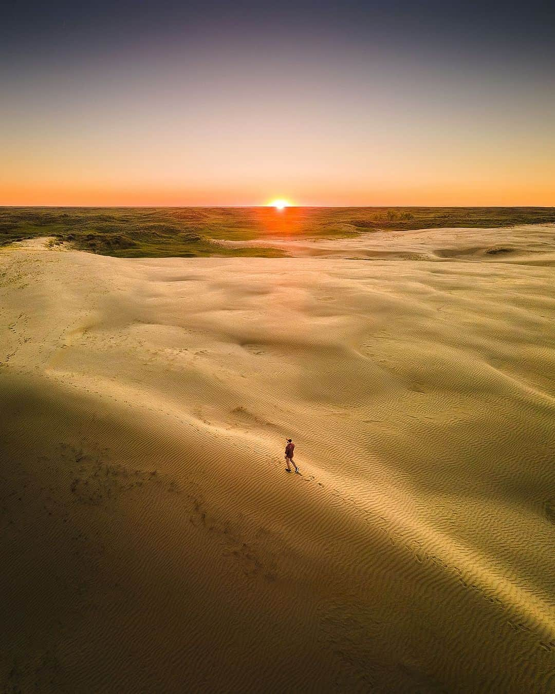 Explore Canadaのインスタグラム：「This is Saskatchewan! ✨ The Great Sandhills is one of Canada’s largest set of active sand dunes, and is protected within the Great Sandhills Ecological Reserve.   Ascend the towering dunes spanning an impressive 1,900 square kilometers (1180 square miles) and be amazed by the ever-changing landscape that dances before your eyes. These dunes are in constant motion, creating a new vista every day!  When you’re ready to take a break from the dunes, the Town of Leader awaits, offering a welcoming base for your adventures. Discover a vibrant community with art galleries, museums and antique shops to explore. 🎨🏛️🛍️  📷: @herry.with.an.e  📍: @tourismsask   #ExploreSask  [Image description: An aerial view of a person walking across a large sand dune. A sun sits just above the horizon.]」