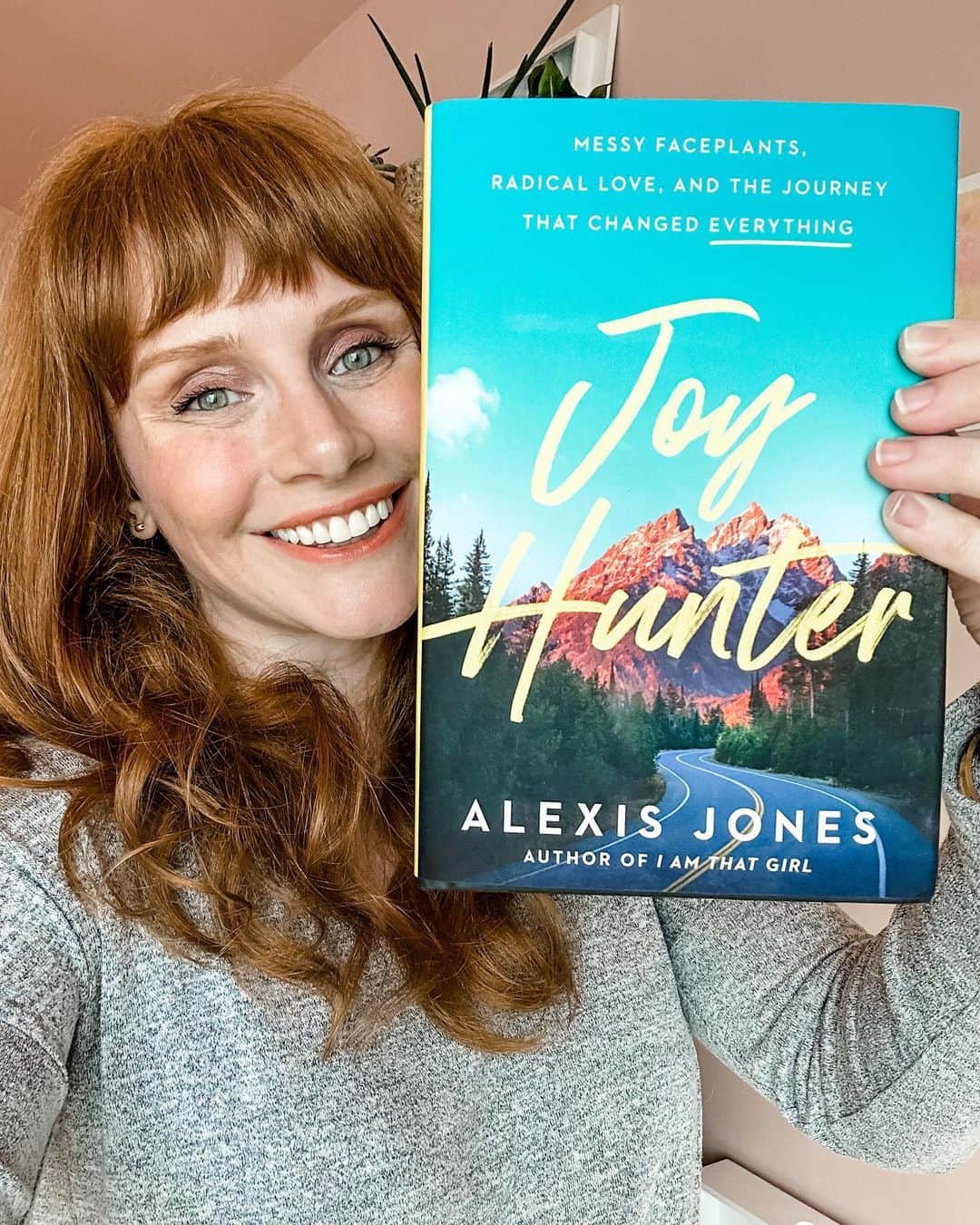 ブライス・ダラス・ハワードのインスタグラム：「My dear friend @alexisjones just launched her new book #JoyHunter TODAY!!! ⁣ ⁣ It’s a soulful memoir and wild journey about love, loss, heartbreak, adventure and finding JOY in the midst of life’s wonderful and messy faceplants -- it's a fantastic read!!⁣ ⁣ Add it to your summer reading list and order it today at the link in bio 🔗⁣ ⁣ [ID: Wearing a grey long sleeve t-shirt, BDH smiles and holds a copy of Alexis Jones’ “Joy Hunter” next to her face. The book cover has a photograph of a stunning  blue sky and mountain range. Over it in yellow handwritten font is the title “Joy Hunter.”]」